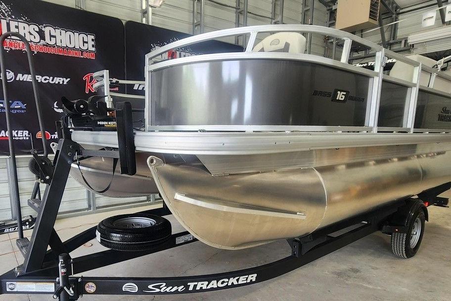 2026 Sun Tracker Bass Buggy 16 DLX pontoon boat on trailer in showroom.