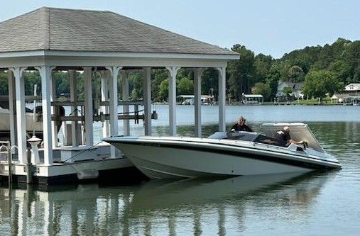 A 1992 Fountain Fever boat docked beside a lakeside pavilion.