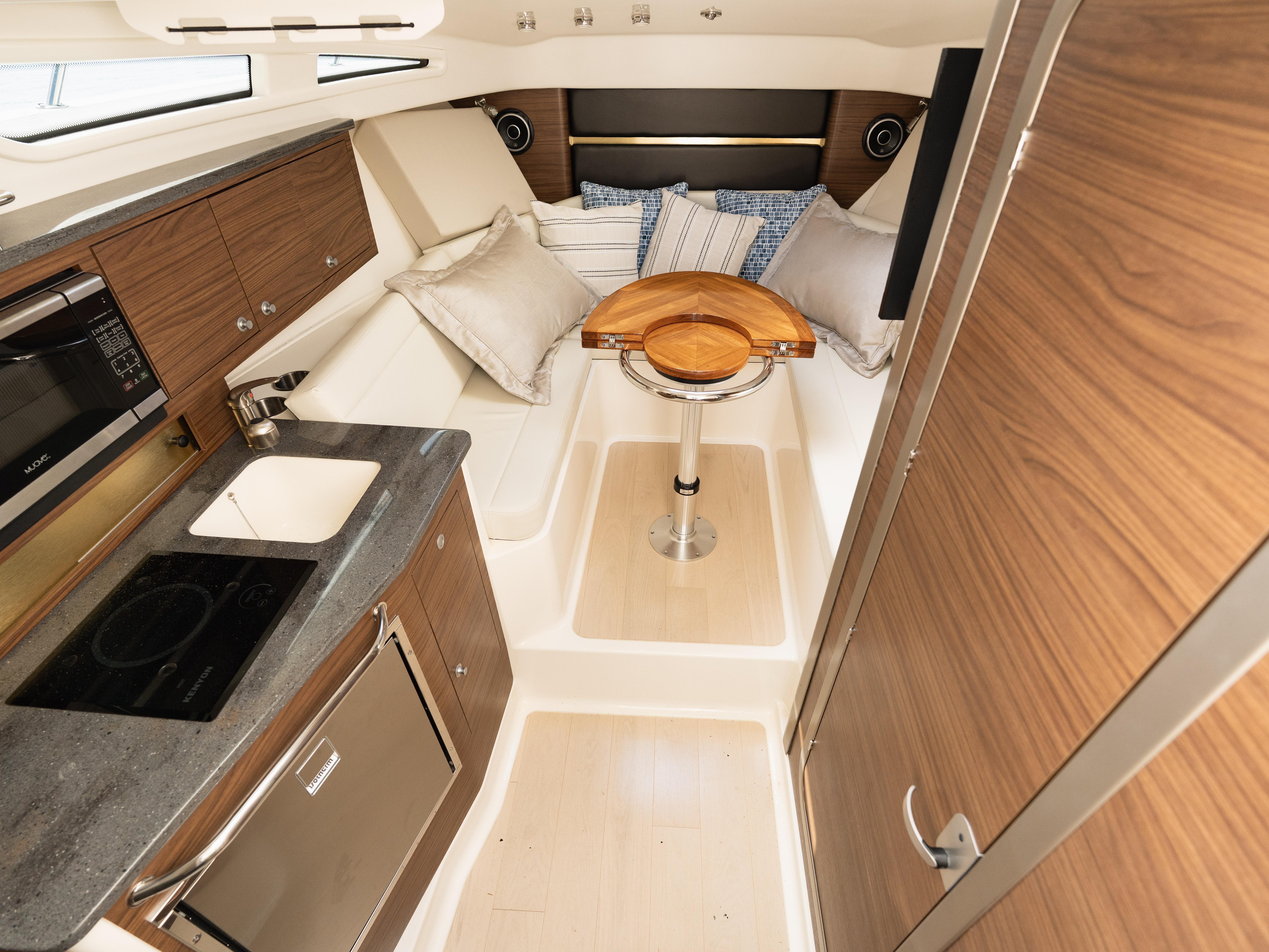 Interior of 2020 Boston Whaler 325 Conquest Pilothouse with modern kitchen and cozy seating area.