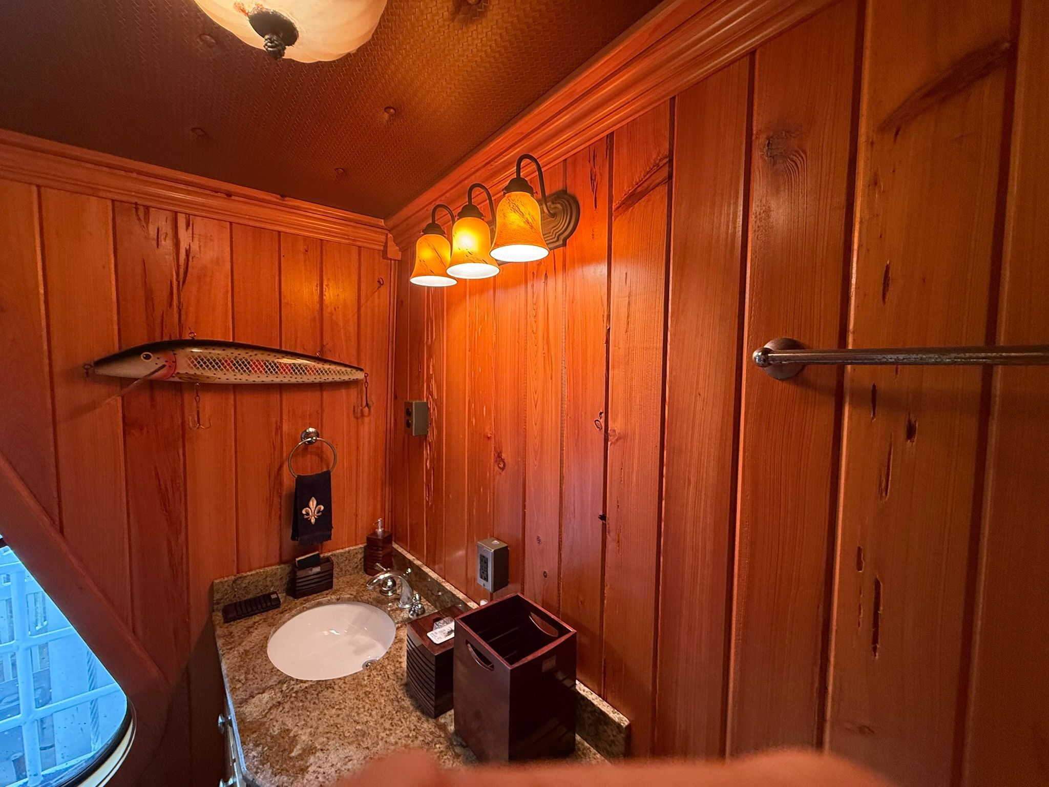 A cozy bathroom with wood paneling, a sink, and decorative lighting.