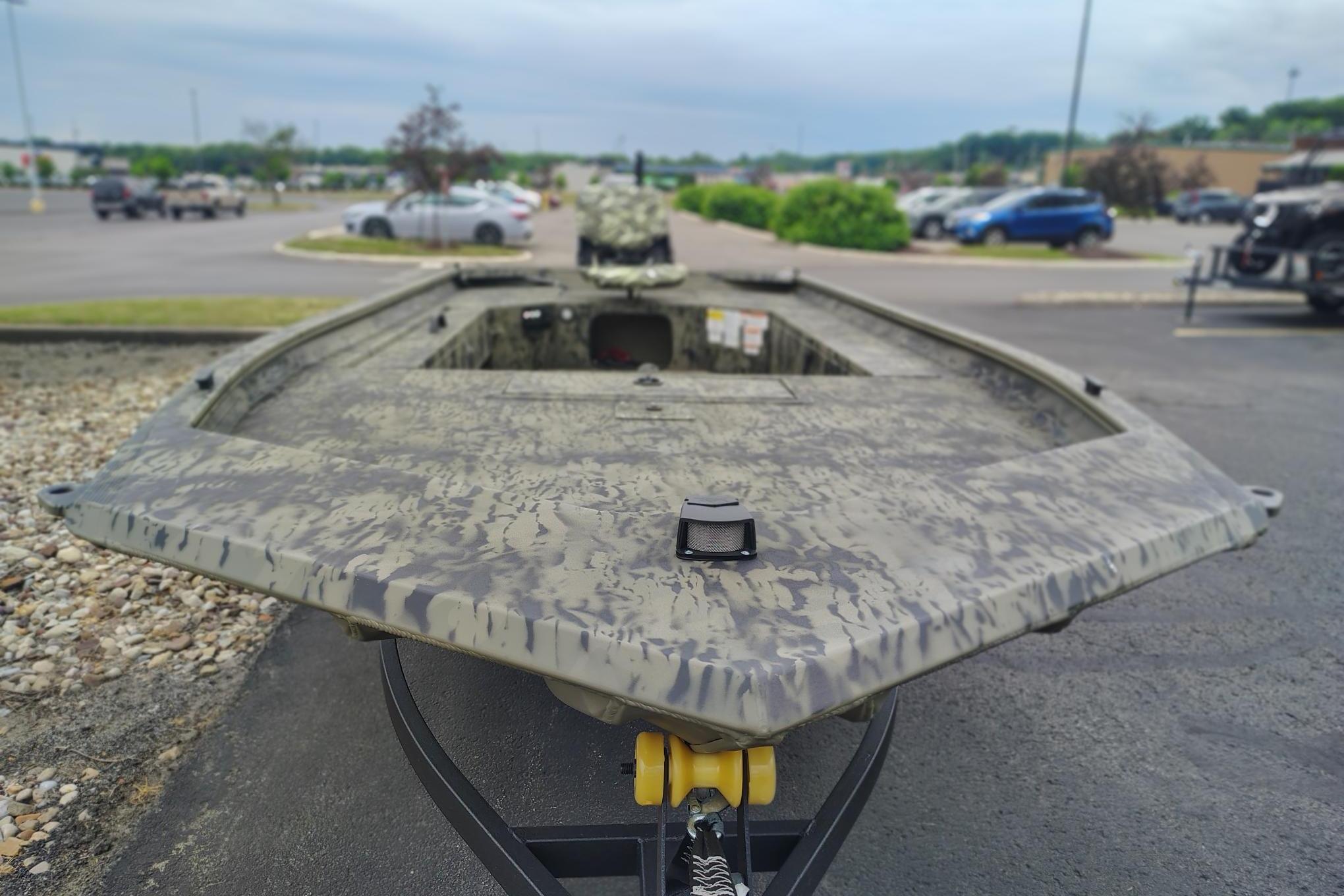 2026 Tracker Grizzly 1654 T Sportsman boat in a parking lot, showcasing camouflage design.