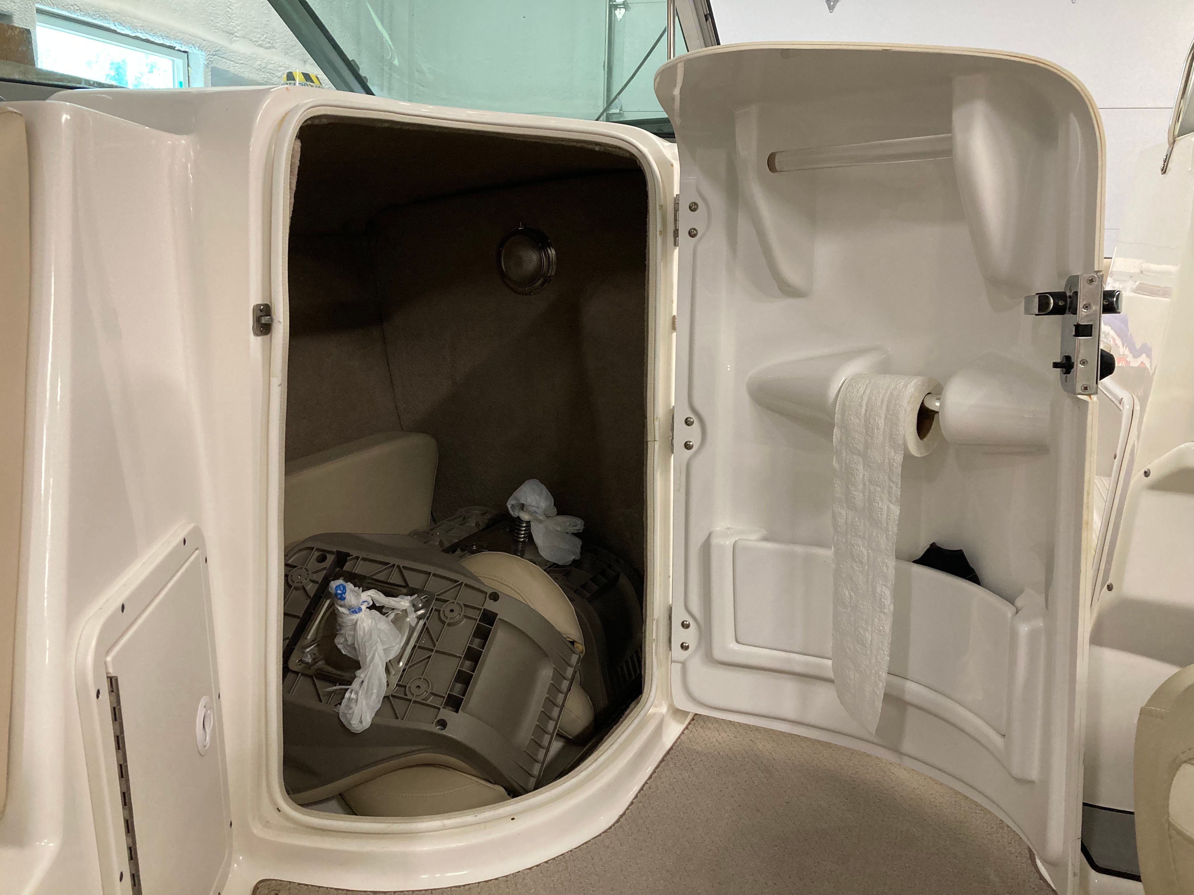 Interior of a boat with storage space and a toilet paper holder.
