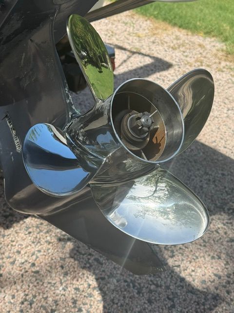Close-up of a shiny boat propeller on gravel.