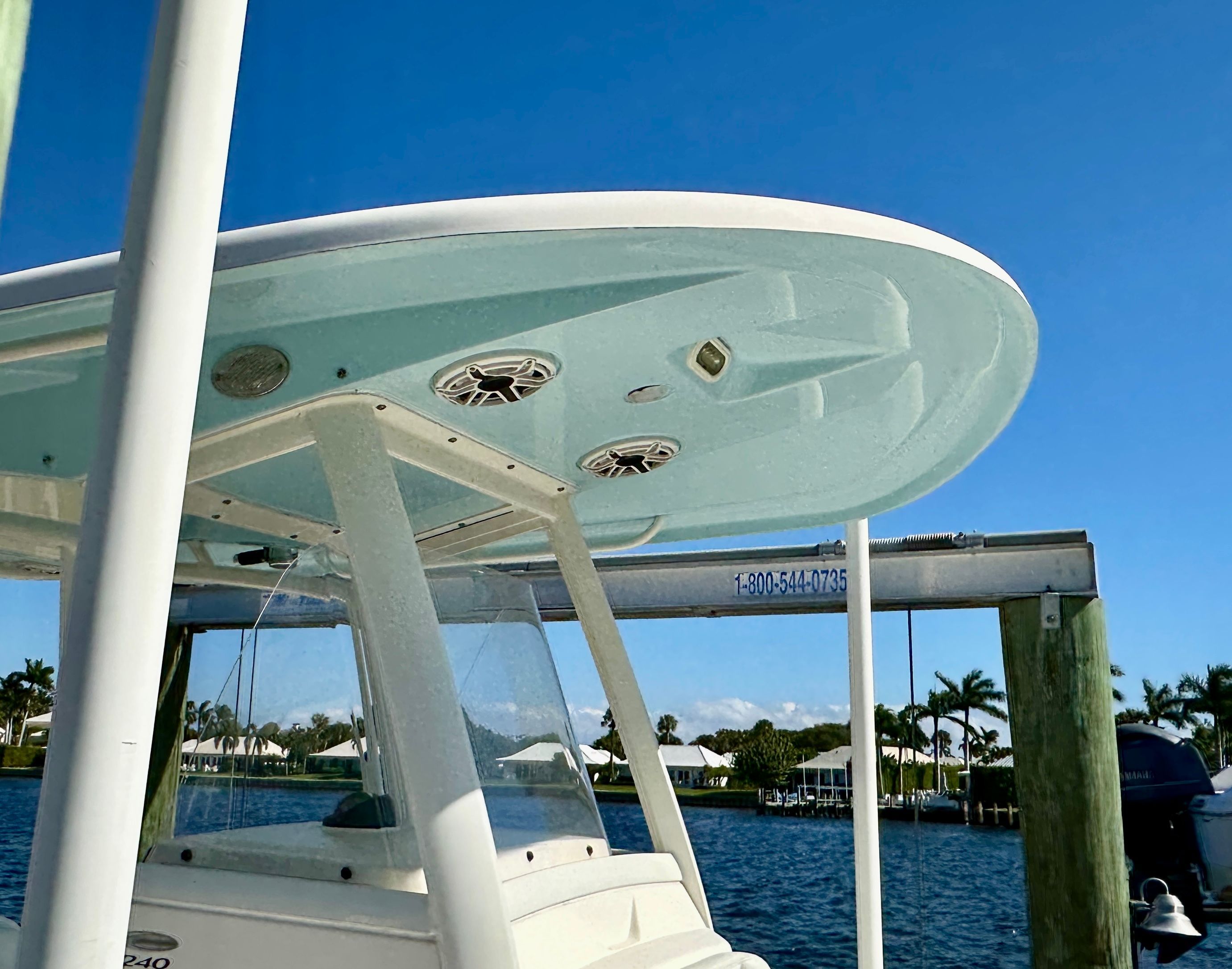 A 2022 Cobia 240 Center Console boat is docked. The sky is clear and blue.