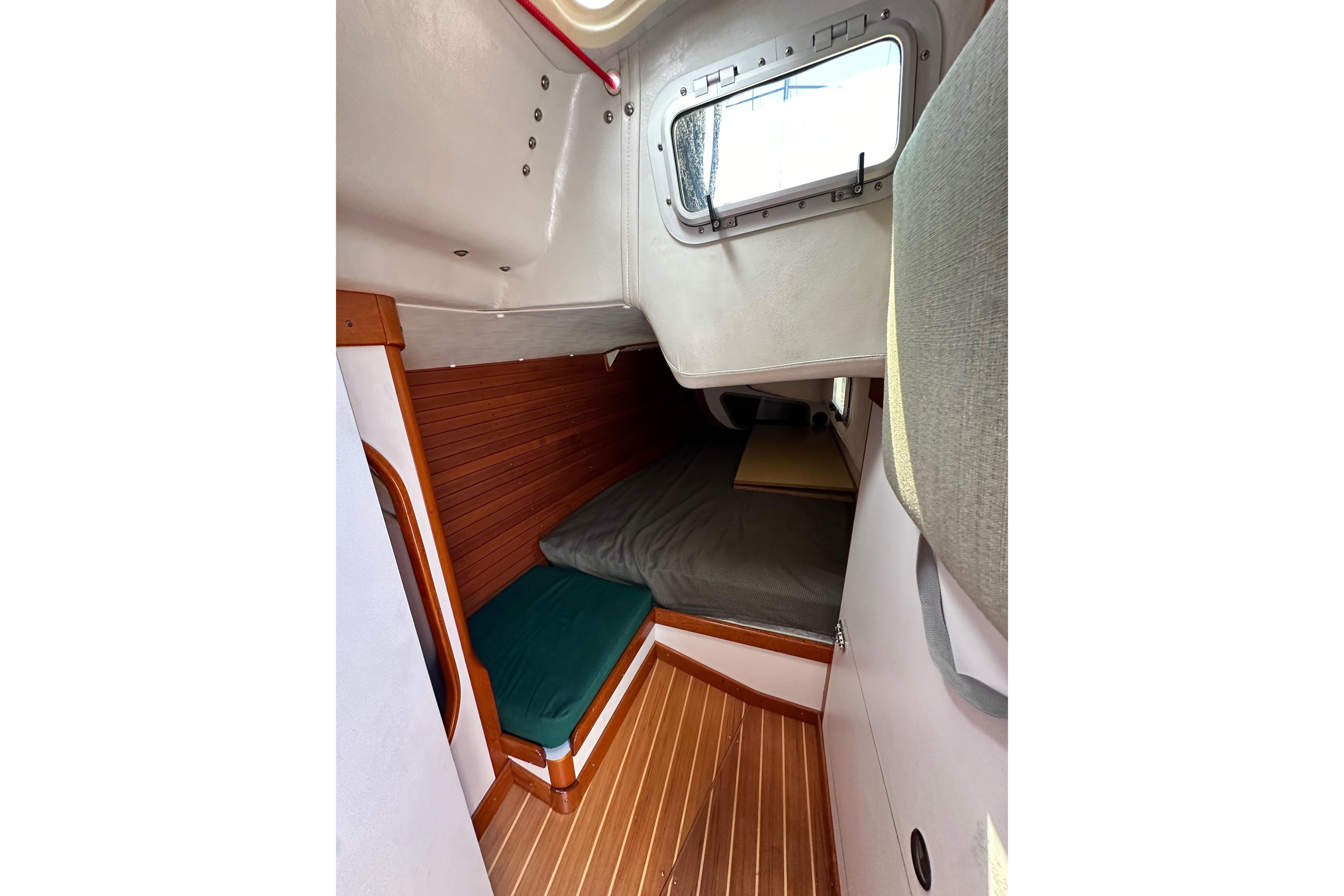 Interior cabin of 1996 J Boats J/120 sailboat with wooden flooring and cozy sleeping area.