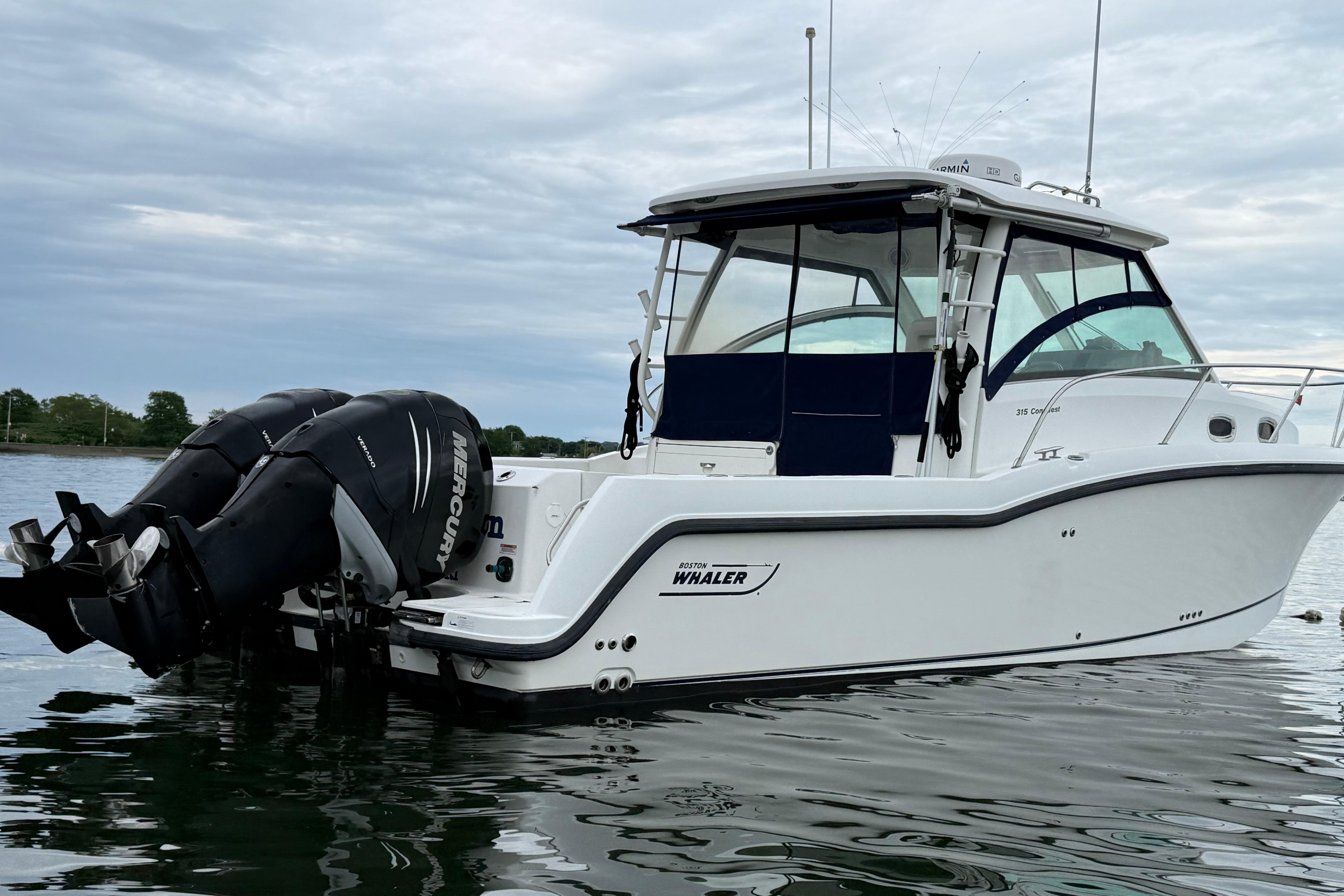 2013 Boston Whaler 315 Conquest boat with twin Mercury engines on calm water.