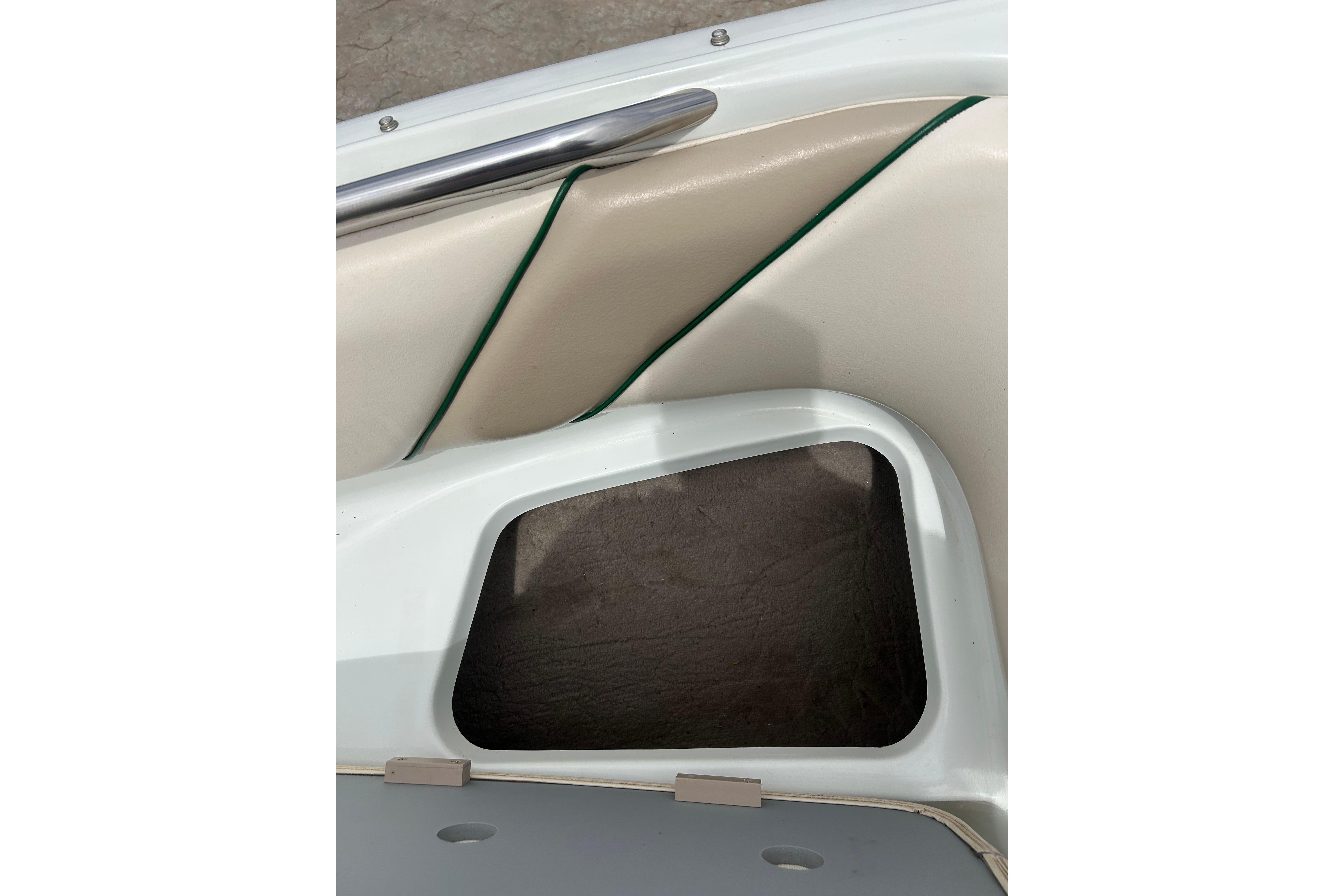Interior detail of a 2000 Starcraft 1810 boat, featuring storage compartment and beige upholstery.