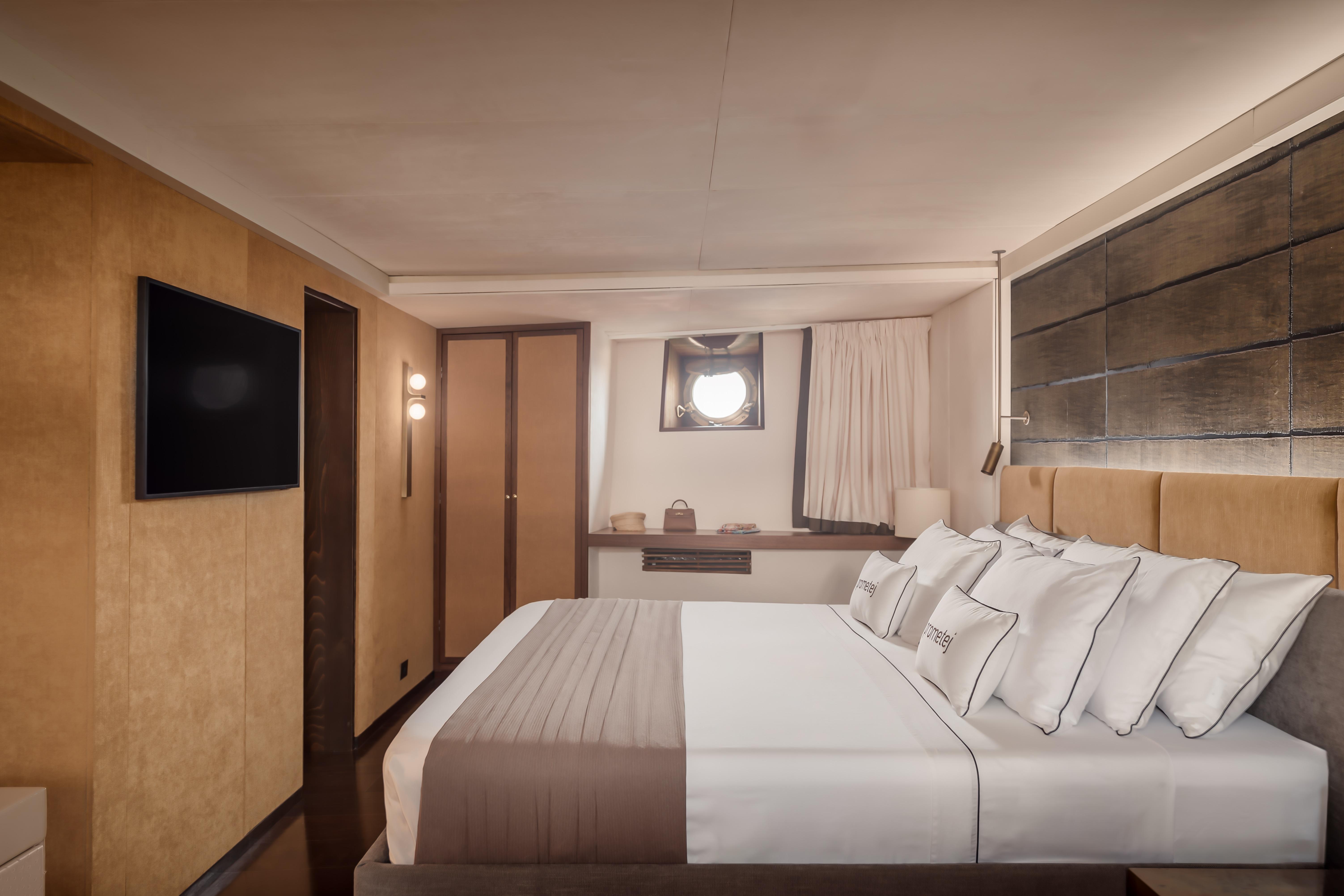 Luxurious bedroom in a 1956 custom converted tugboat, featuring modern decor and porthole window.