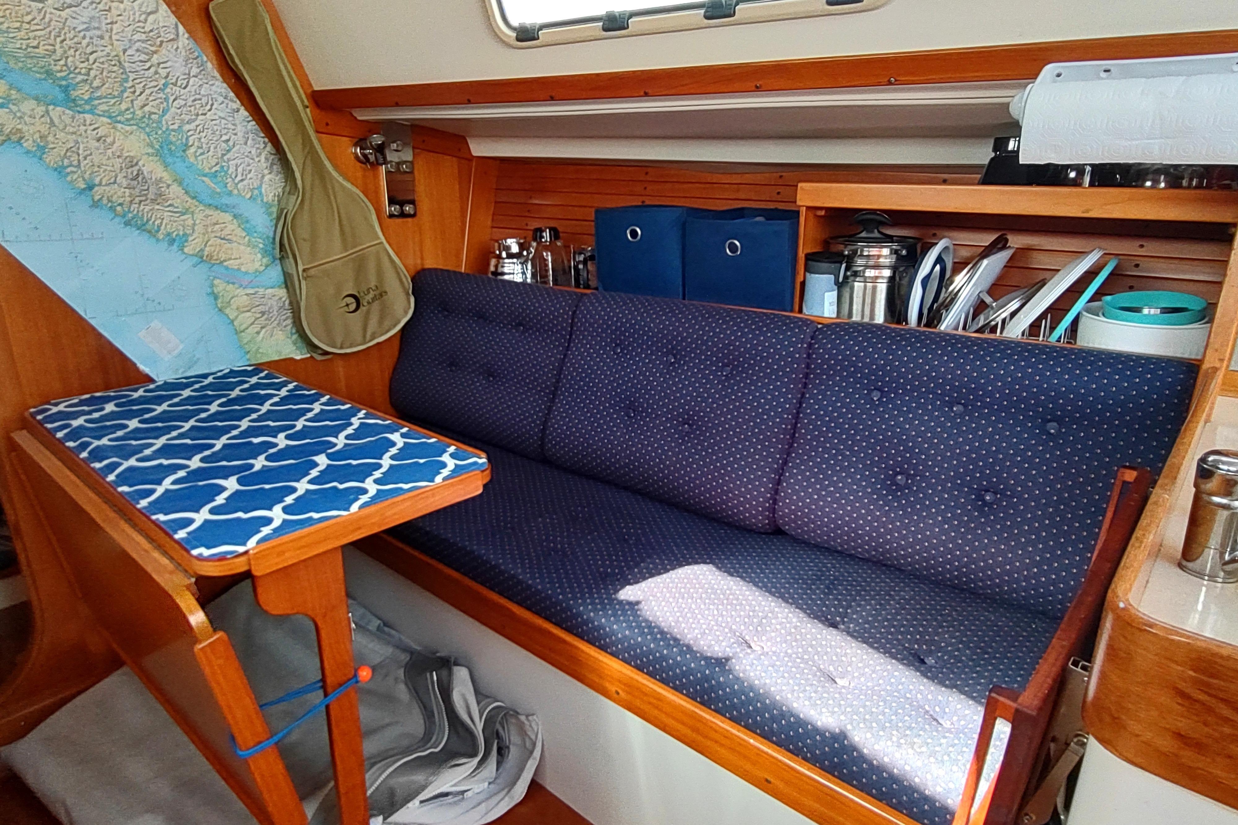 Interior of a 1998 J Boats J/32 sailboat with blue cushioned seating and nautical decor.