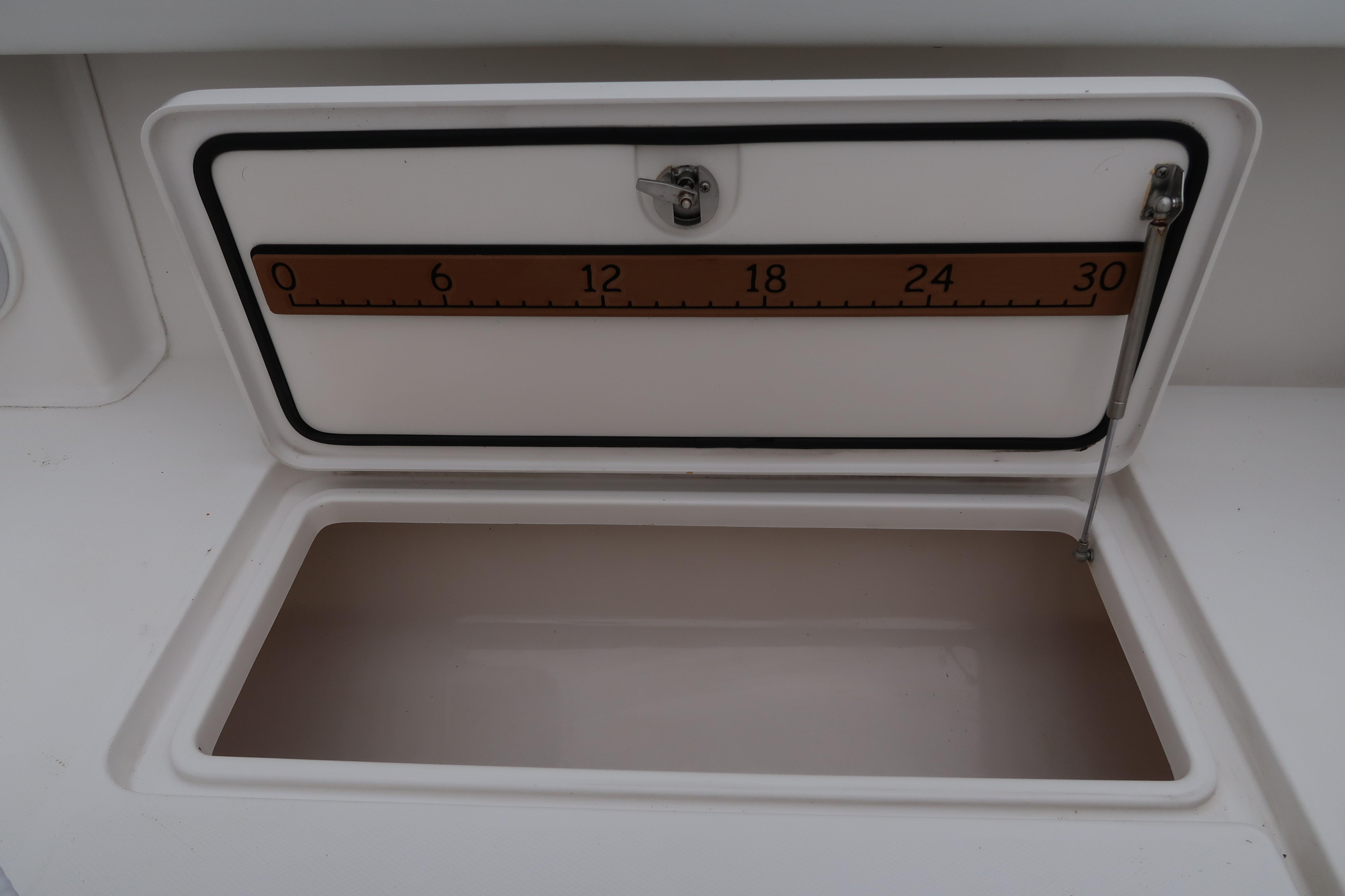 Open storage compartment with measuring scale on a 2016 Invincible 42 Open Fisherman boat.