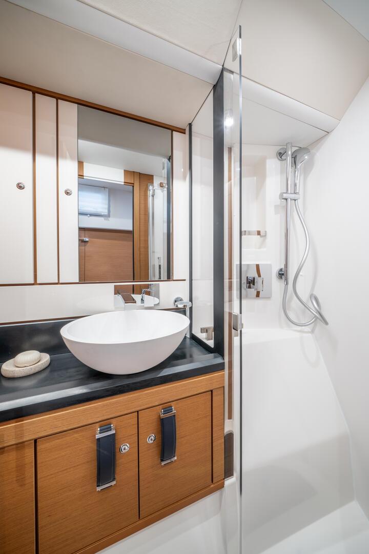 Modern bathroom in 2023 Jeanneau 65 yacht with sleek design and wooden cabinetry.