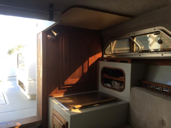 Interior of a 1987 Boston Whaler Cuddy Tower boat, featuring wood accents and compact design.