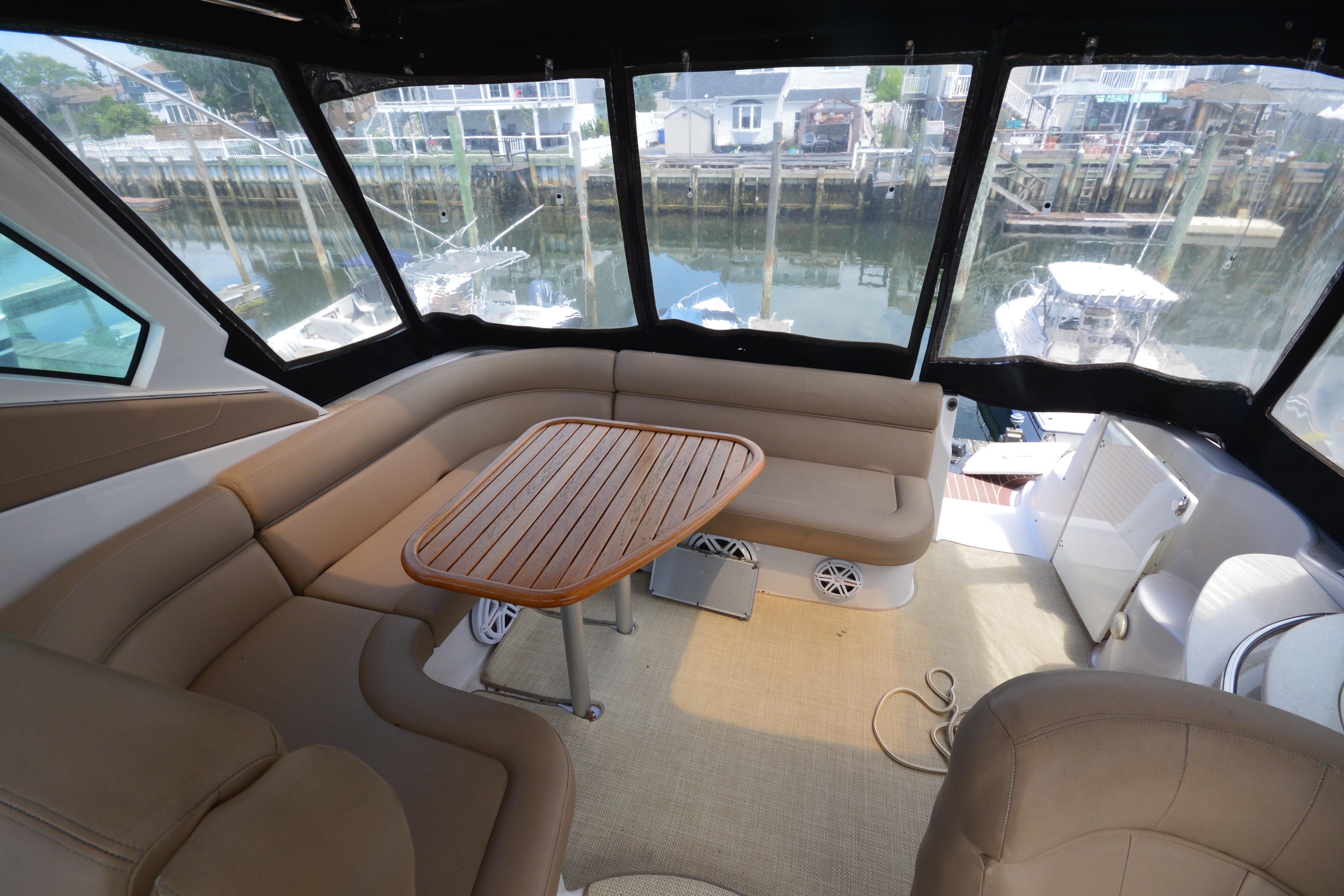 Interior of 2013 Four Winns V375 boat with cushioned seating and wooden table.