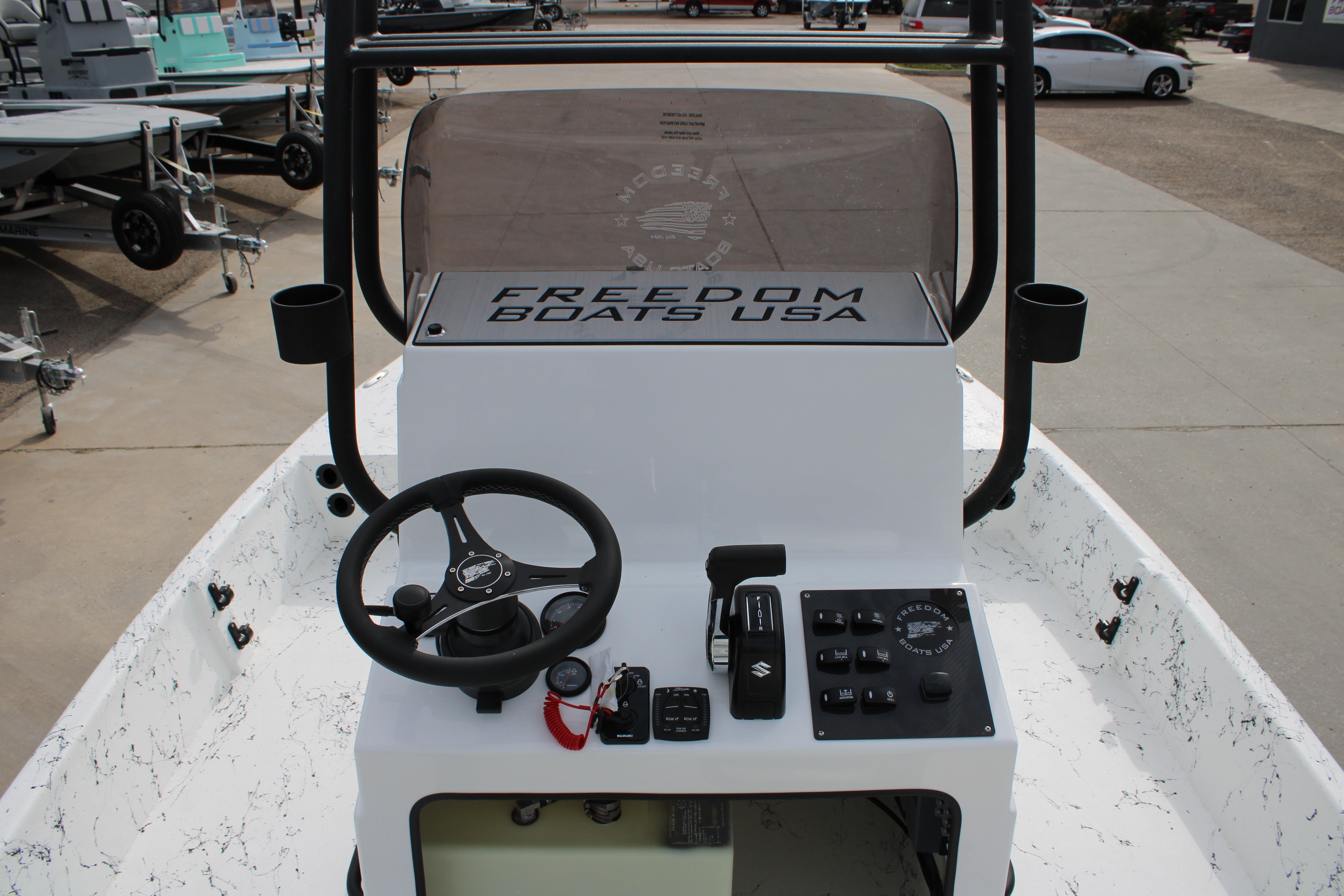 2026 Freedom Boats 19 PATRIOT console with steering wheel and controls, docked outdoors.