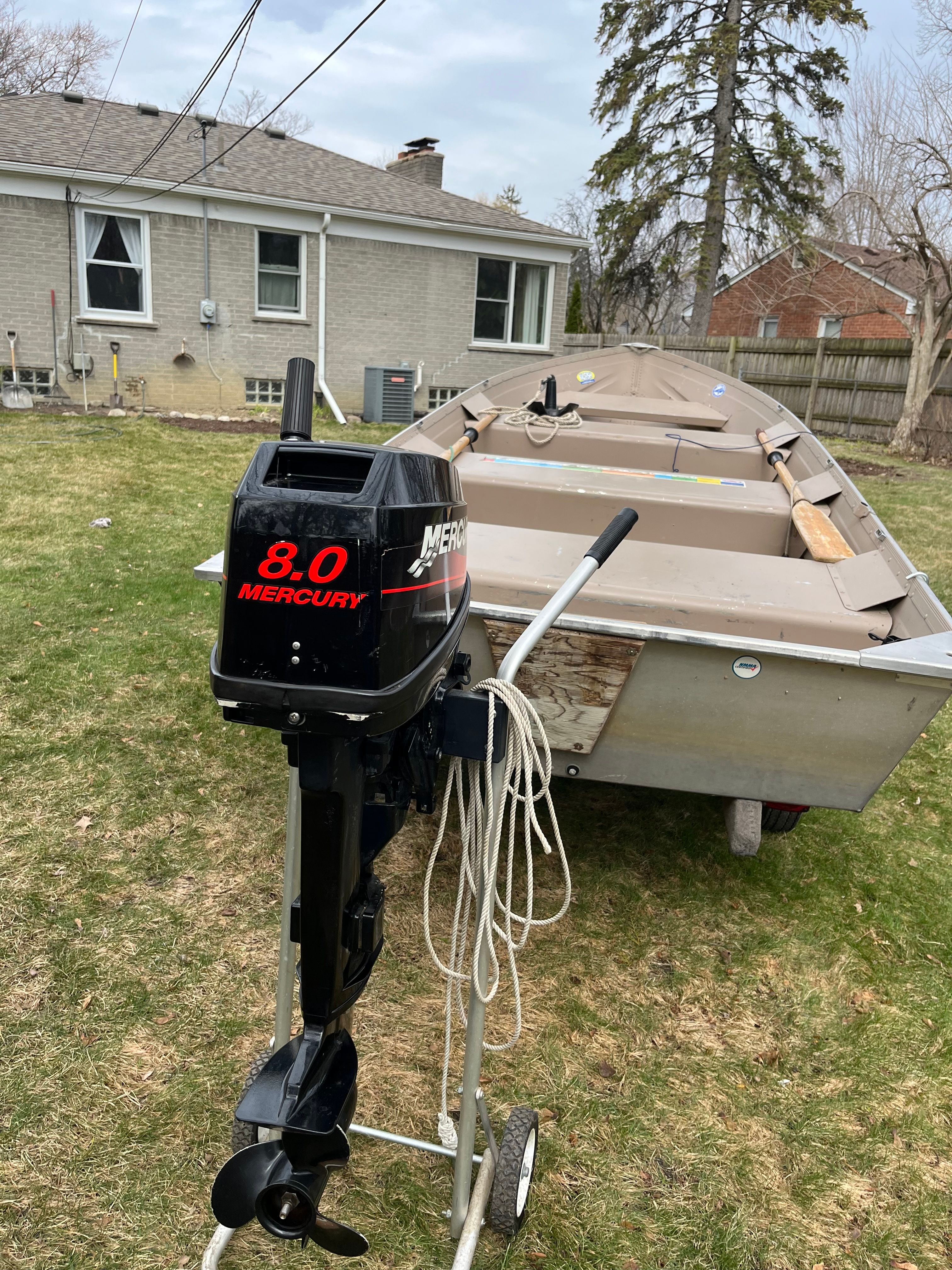 A 2005 Polar Kraft V1460 boat with an 8 HP Mercury outboard motor sits on a lawn.