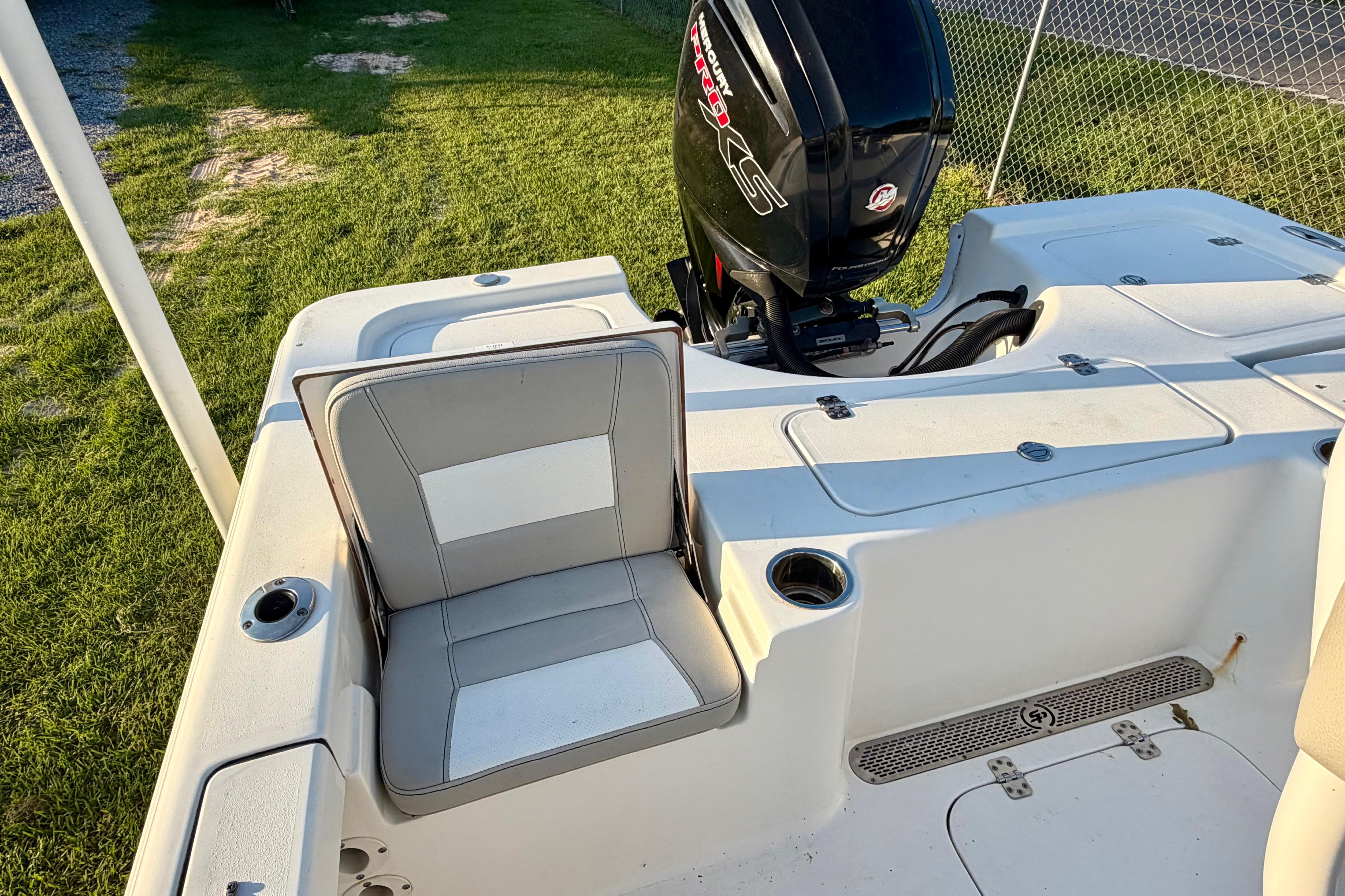 2018 Sea Pro 208 Bay boat with seating and outboard motor, parked on grass.