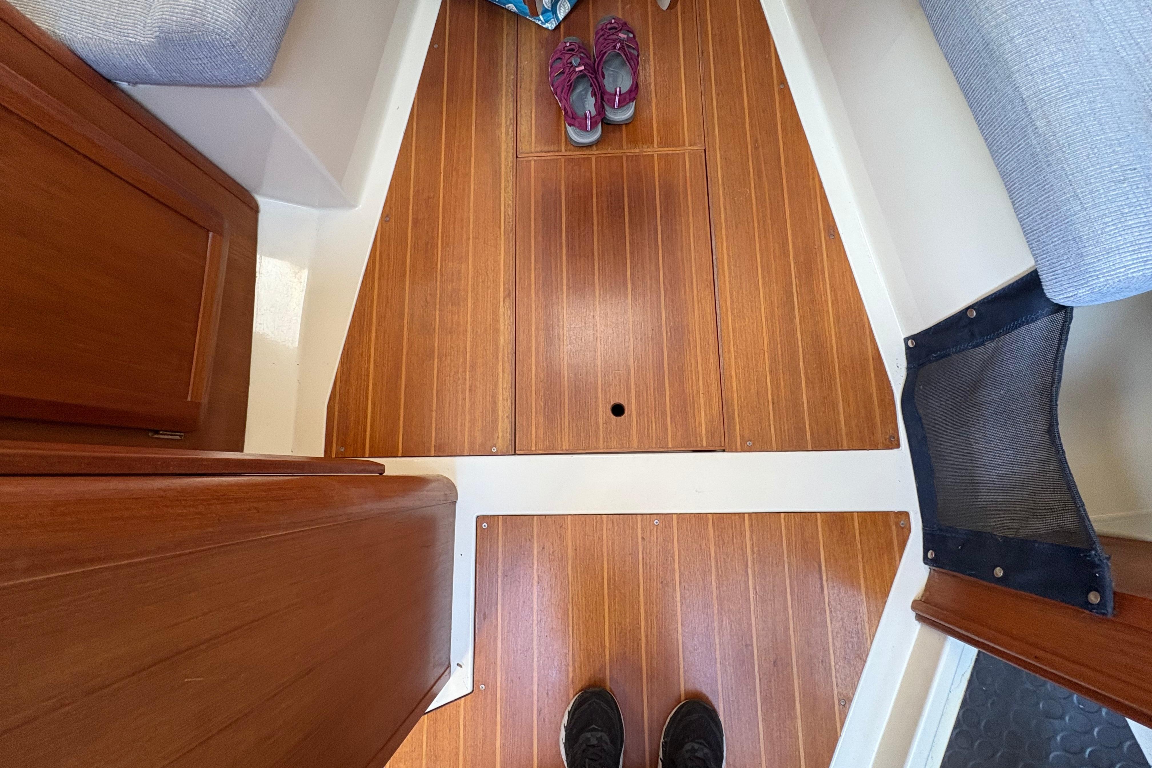Interior view of a 1993 Hunter 28 sailboat with wooden flooring and visible shoes.