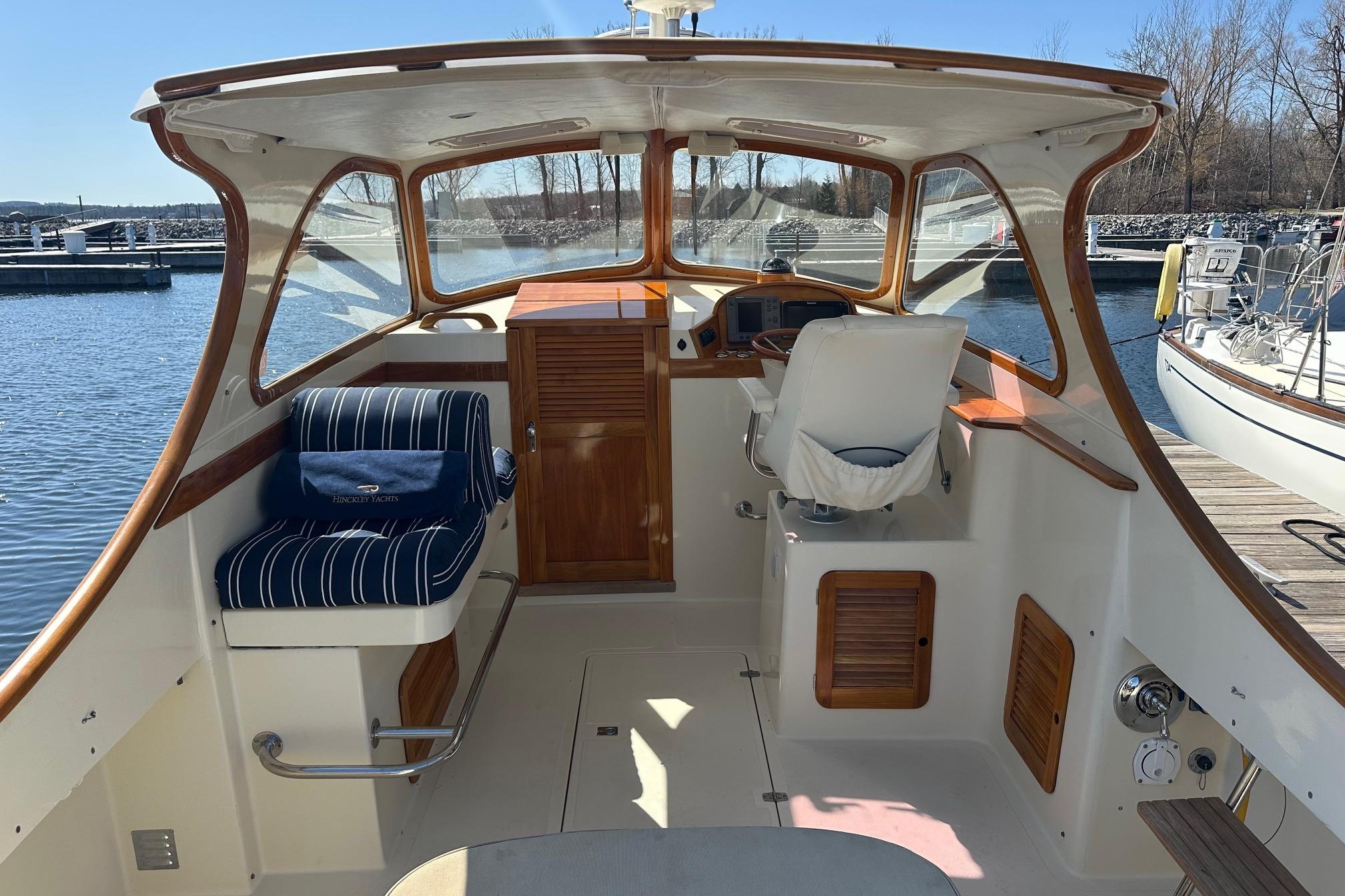 1996 Hinckley Picnic Boat 36 Classic interior with helm and seating, docked by the water.