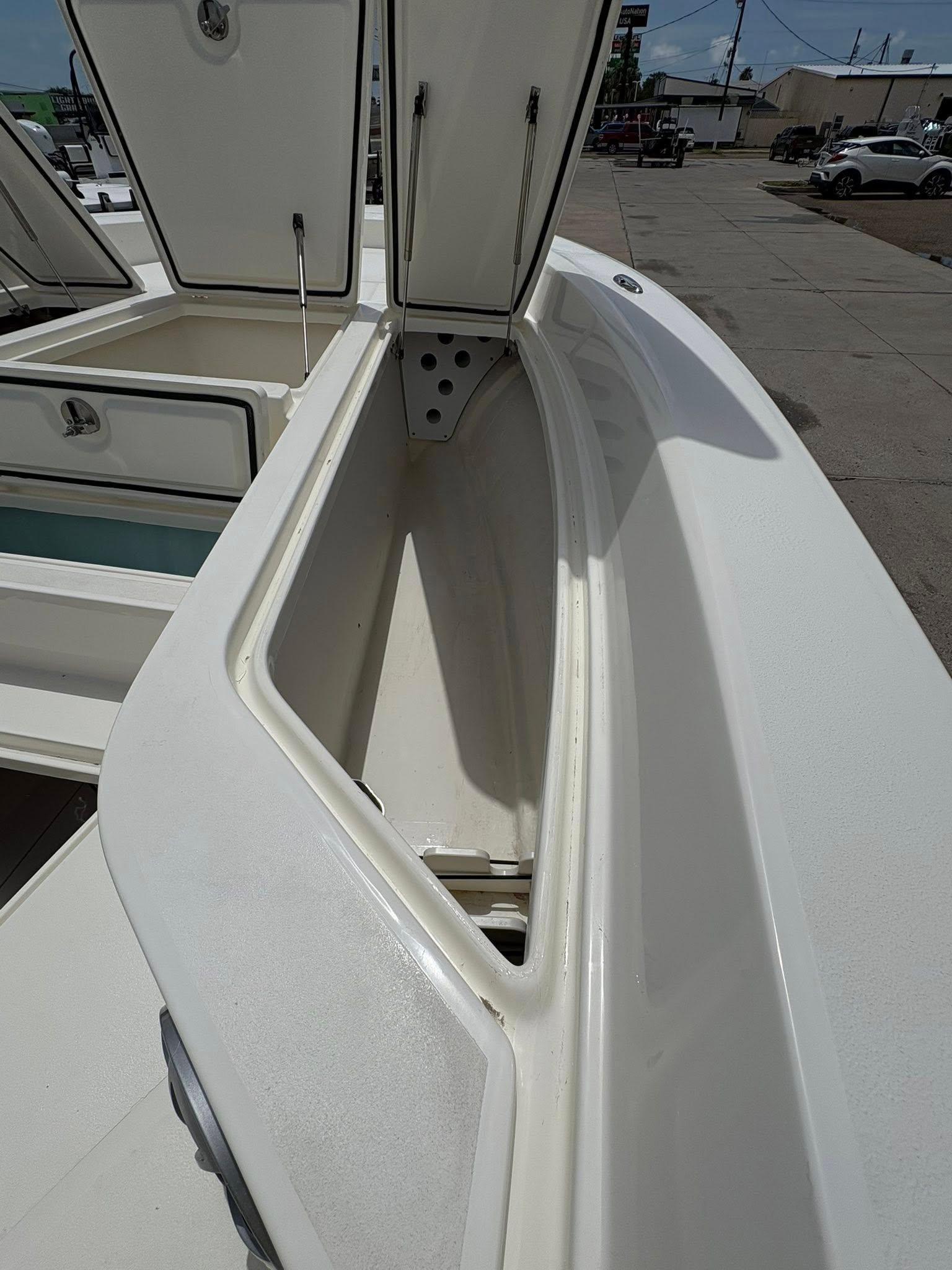 Open storage compartment on 2025 Mako 24 APEX boat, showcasing spacious interior design.