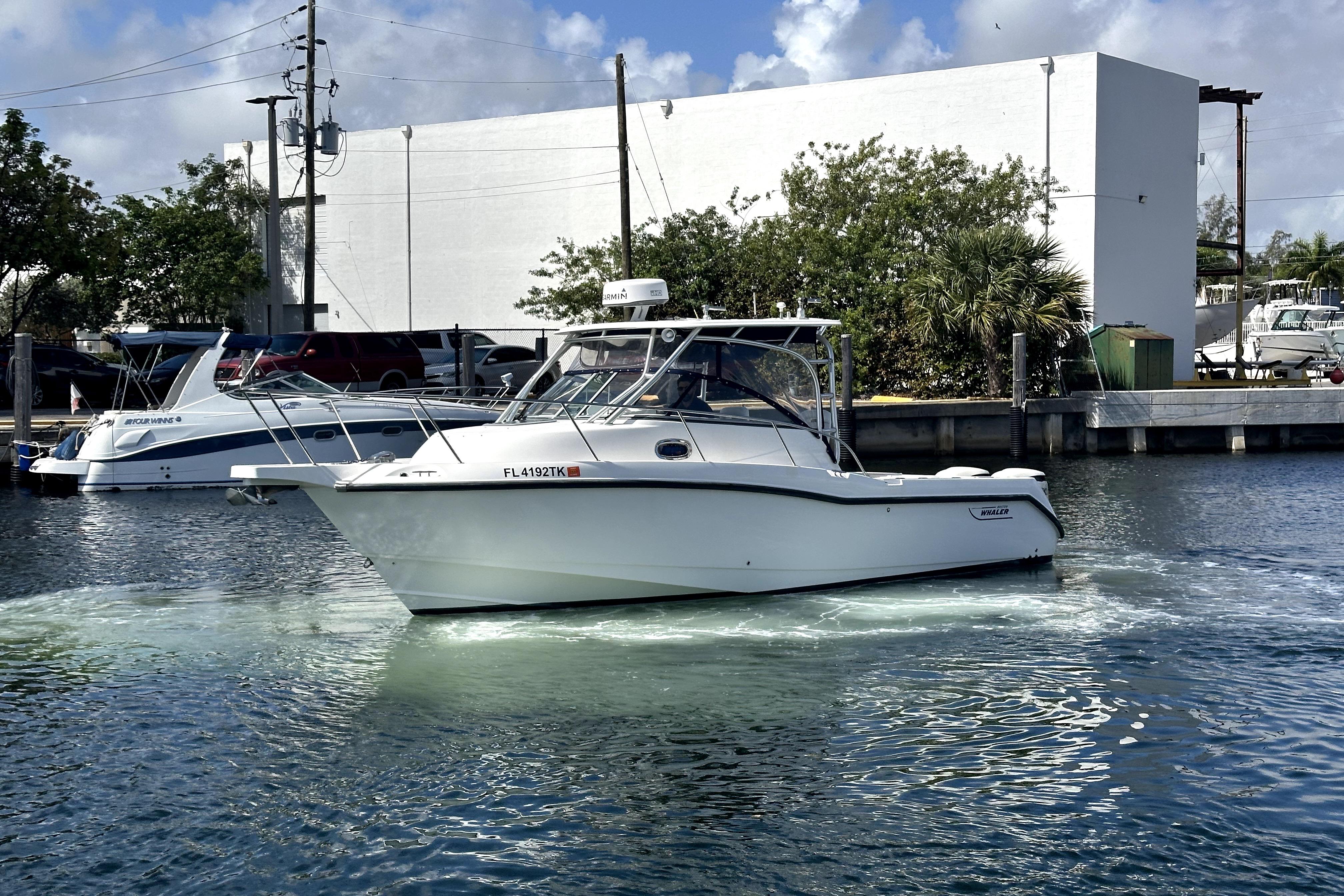 2006 Boston Whaler 285 Conquest boat docked in a marina under a clear sky.