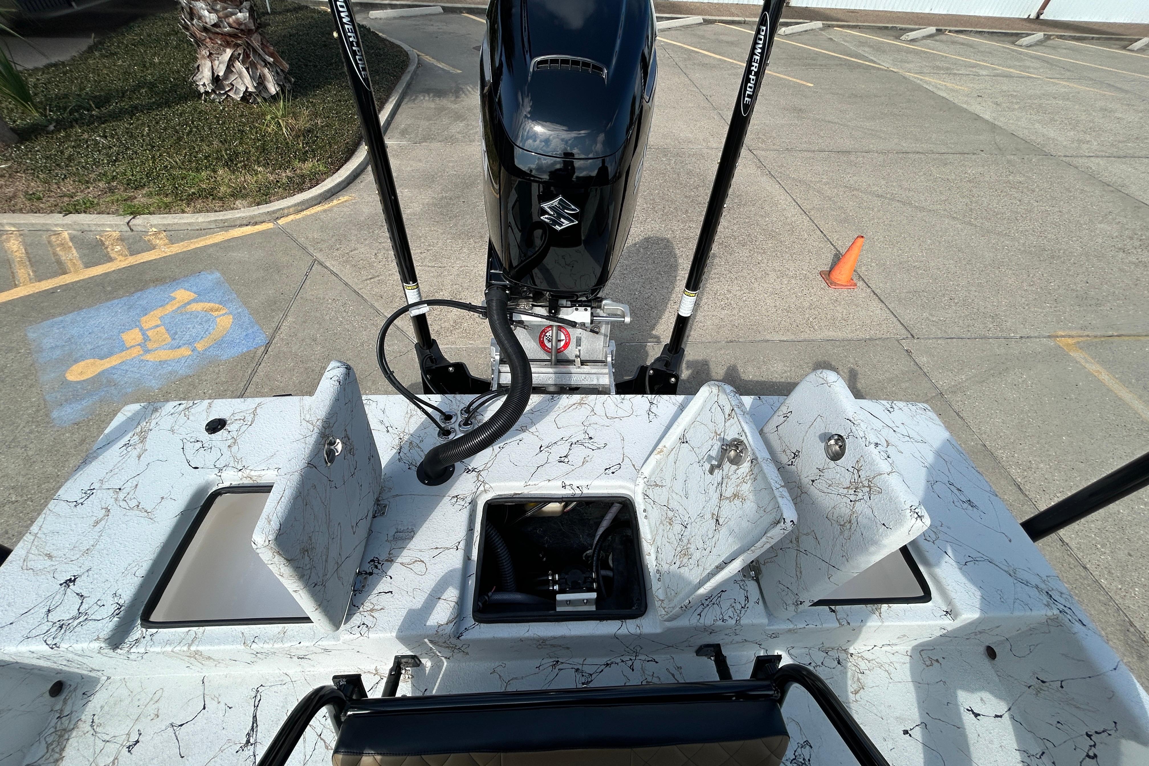 2026 Skuta 24 Vista boat with open storage compartments and outboard motor in a parking area.