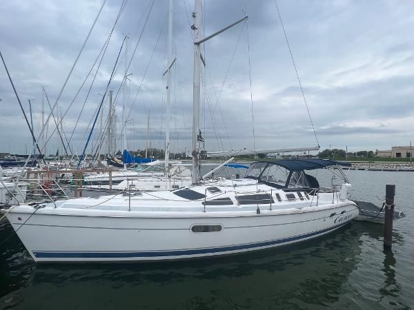 A 2000 Hunter 410 sailboat docked in a marina. It features a white deck and blue canopy.