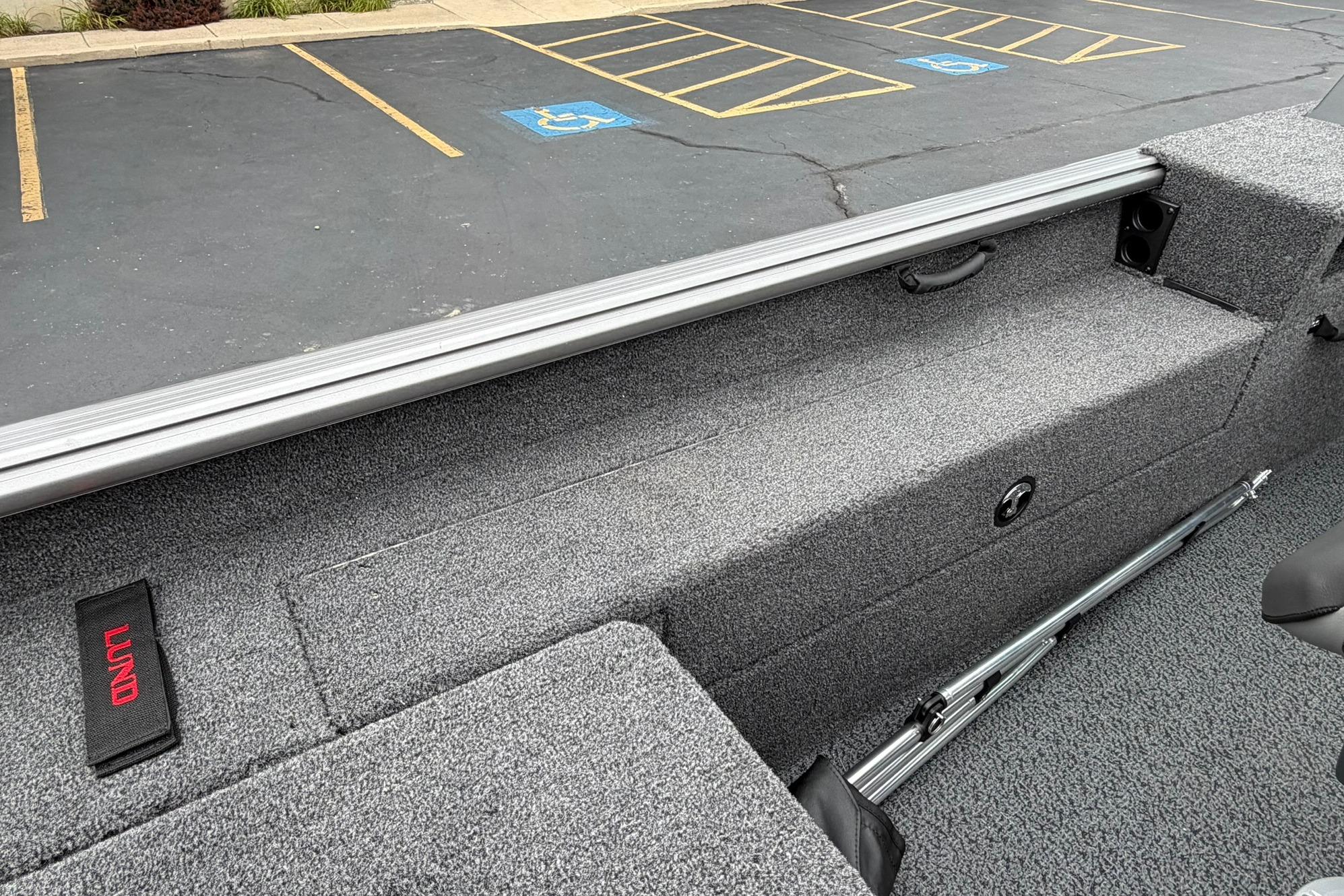 2027 Lund 1875 Impact XS Sport boat interior with gray carpet and storage compartments.
