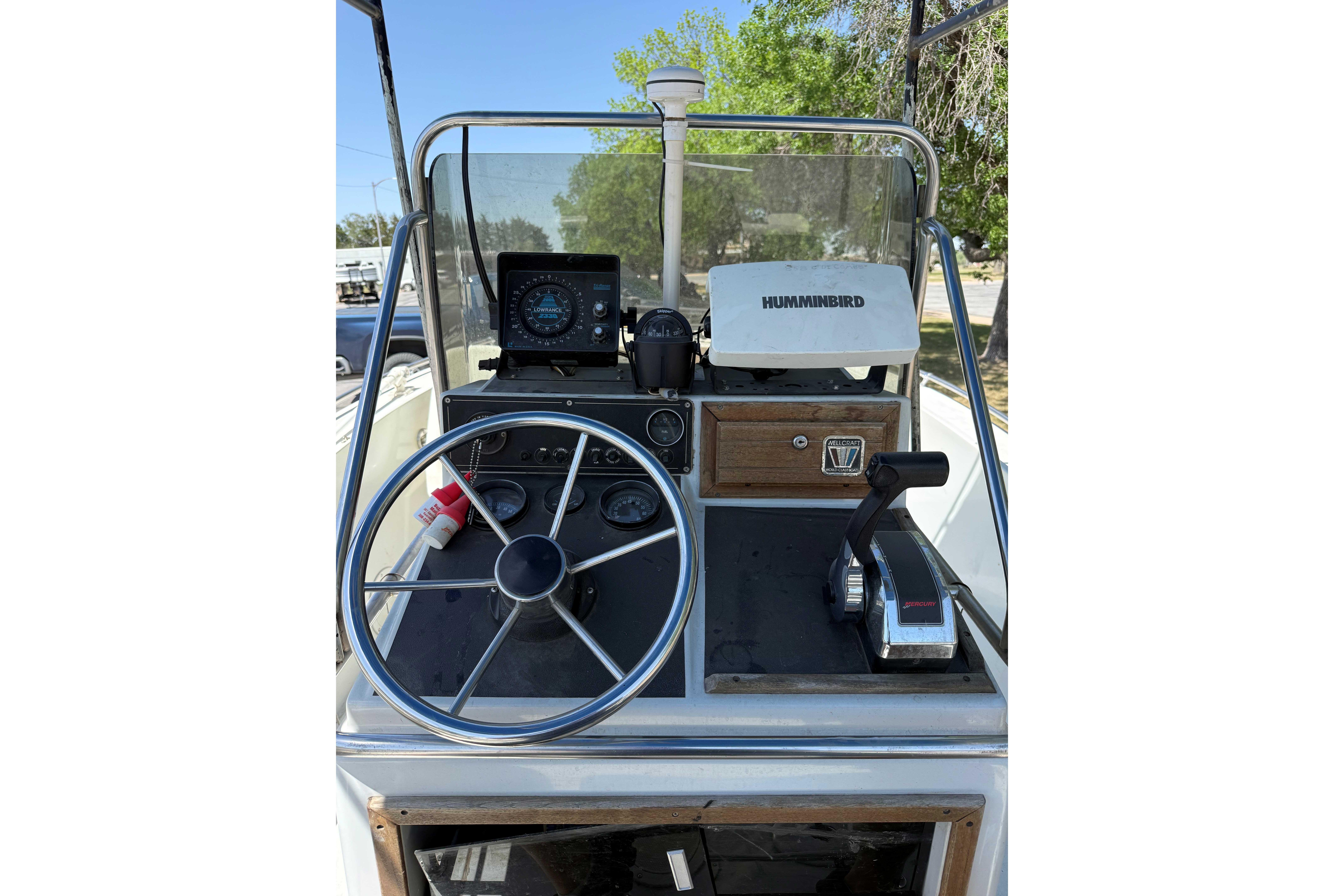 1985 Wellcraft 180 Fisherman boat dashboard with steering wheel and Humminbird equipment.