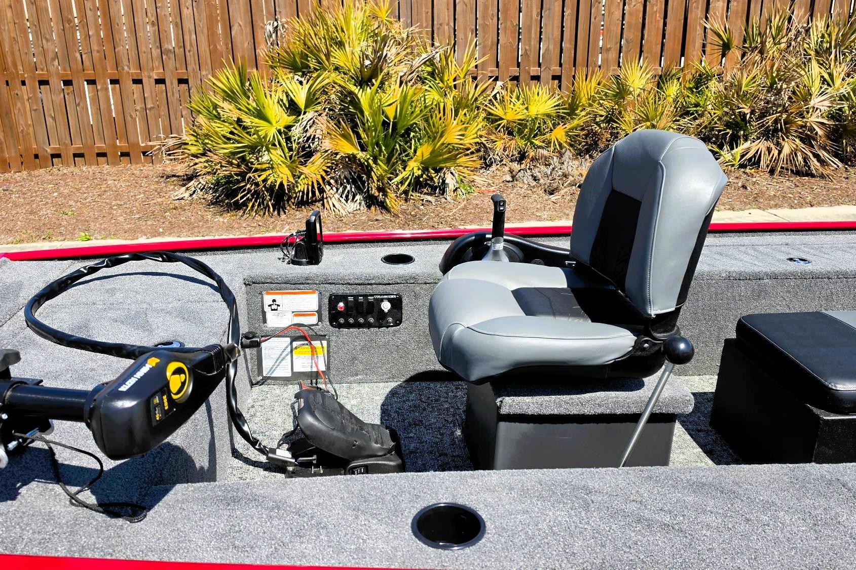 2026 Tracker Panfish 17 boat interior with seating and control panel, surrounded by greenery.