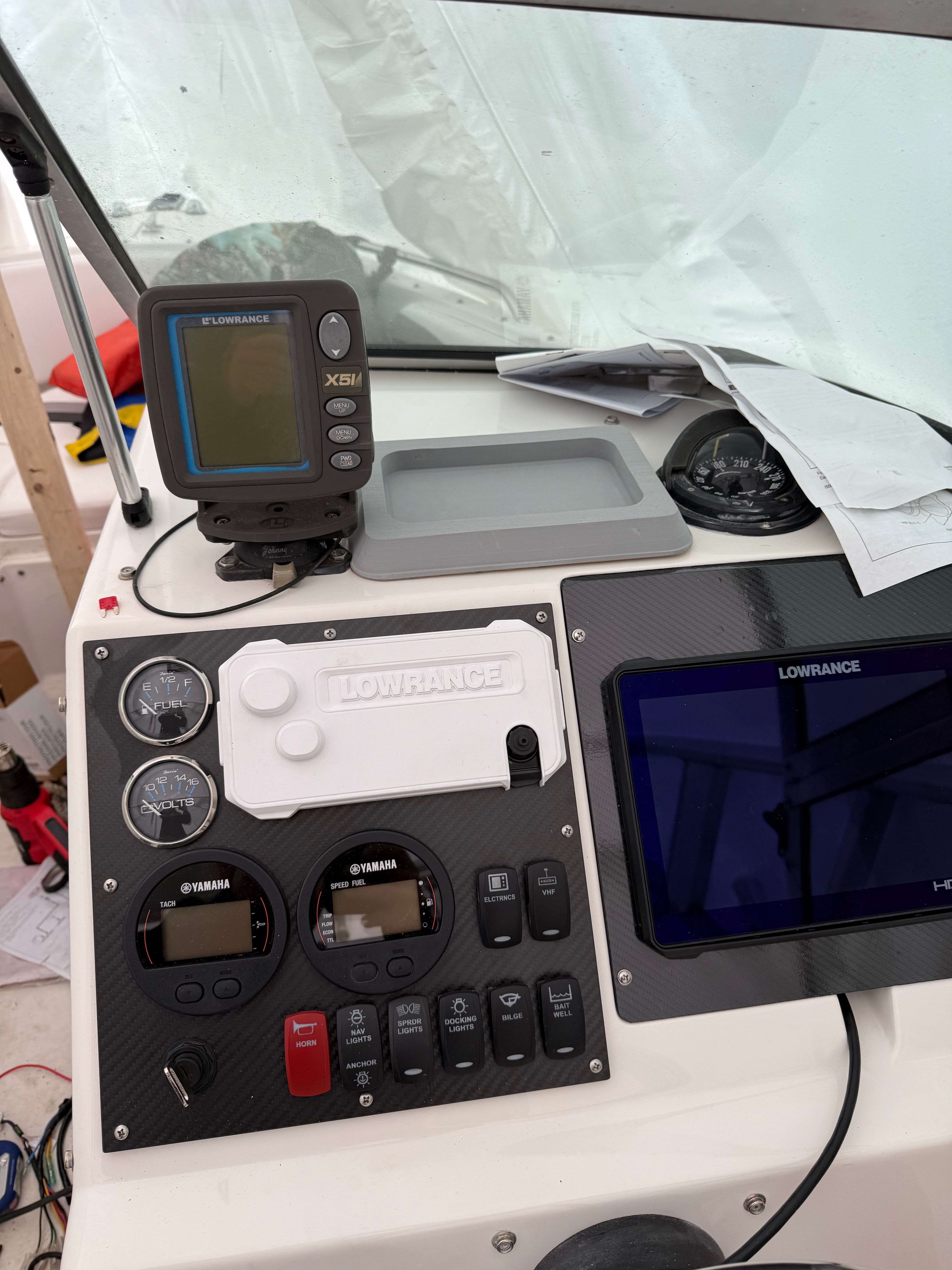 The image shows a boat's dashboard with various instruments and a GPS device.