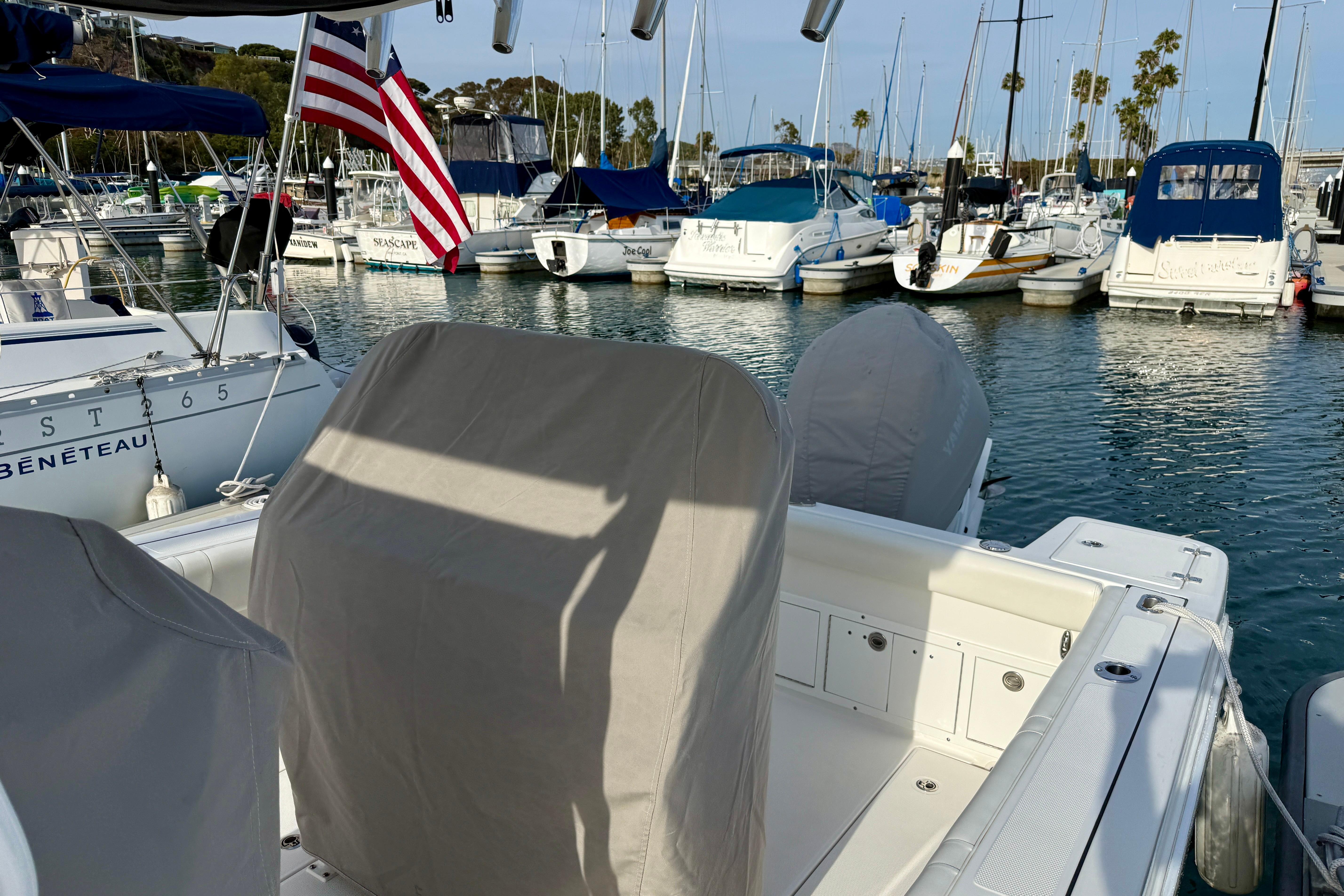 2023 Edgewater 245CC boat docked in a marina with American flag and covered seats.