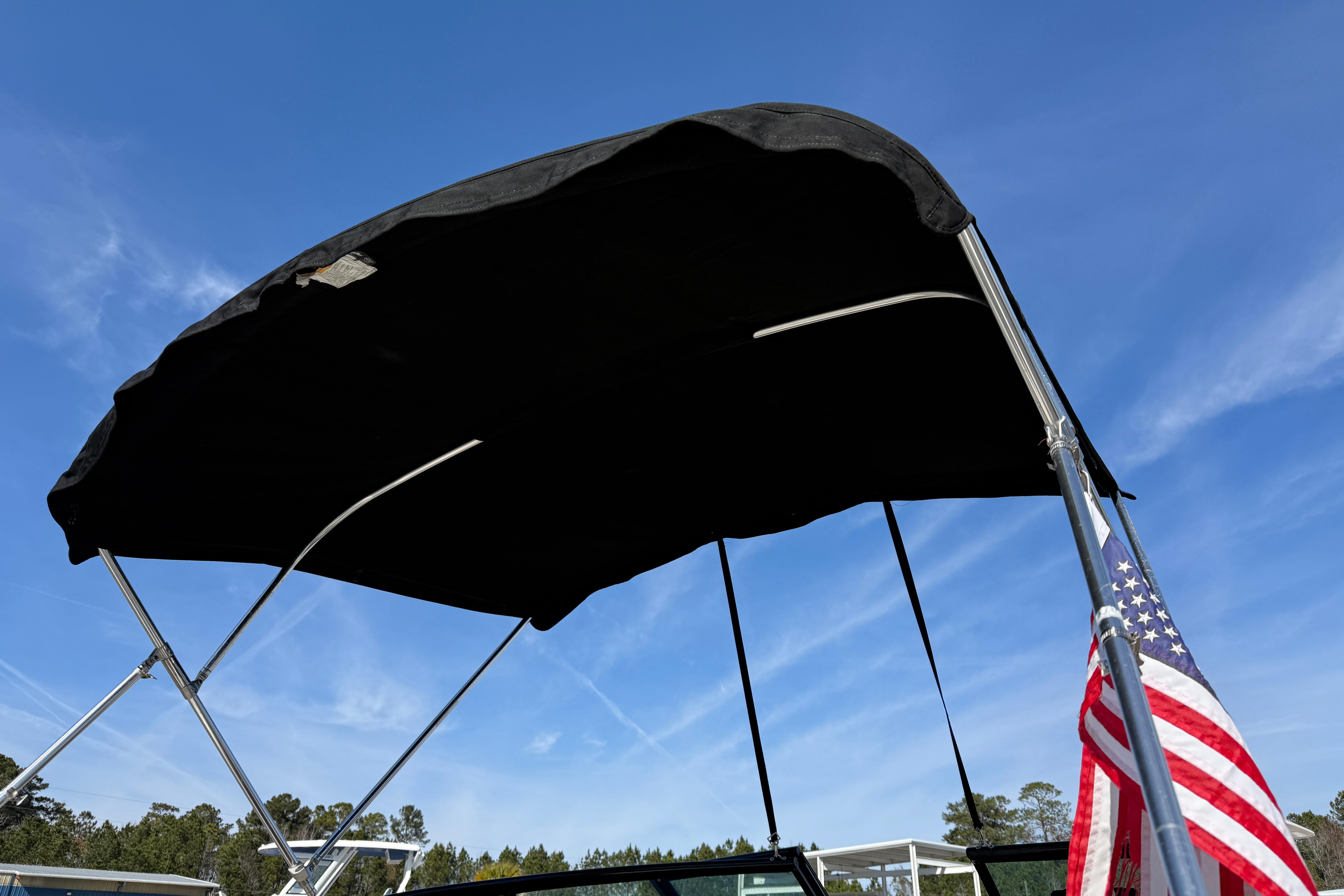 2014 Monterey 197 Blackfin boat with bimini top and American flag against blue sky.
