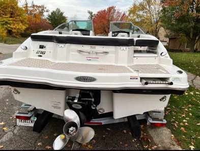 The image shows the stern of a white 2010 Chaparral 216 SSi boat parked on land.
