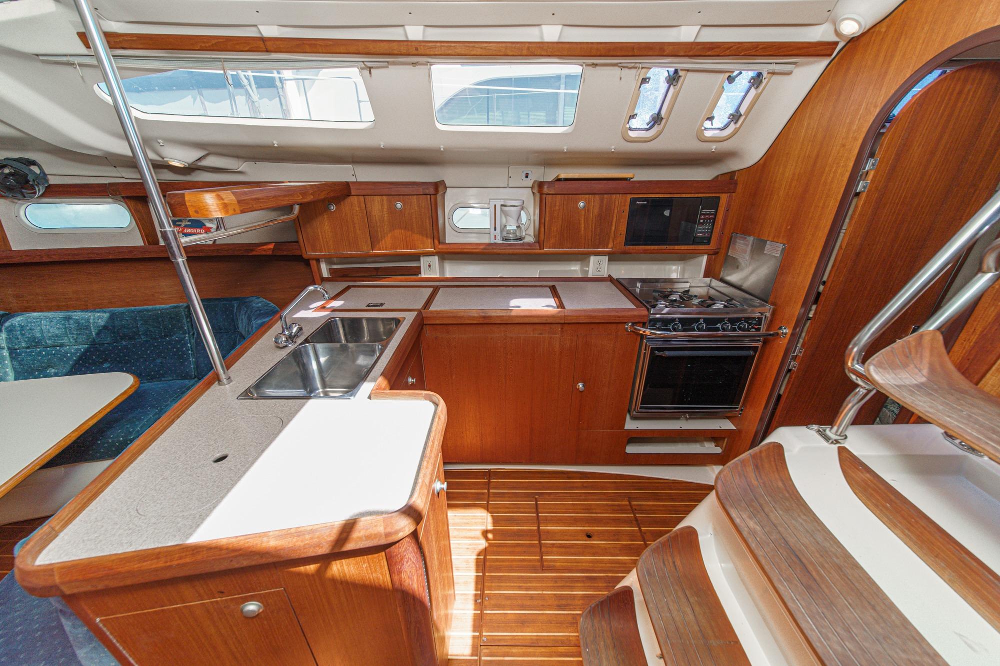 Interior of a 1996 Hunter 376 sailboat featuring a compact kitchen with wood cabinetry.
