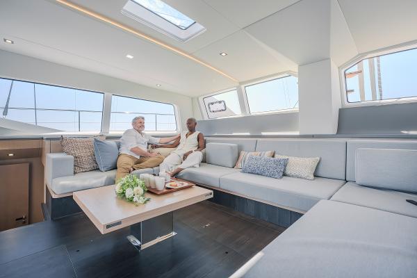Luxurious interior of 2025 Privilege Signature 650 yacht with two people relaxing on a sofa.