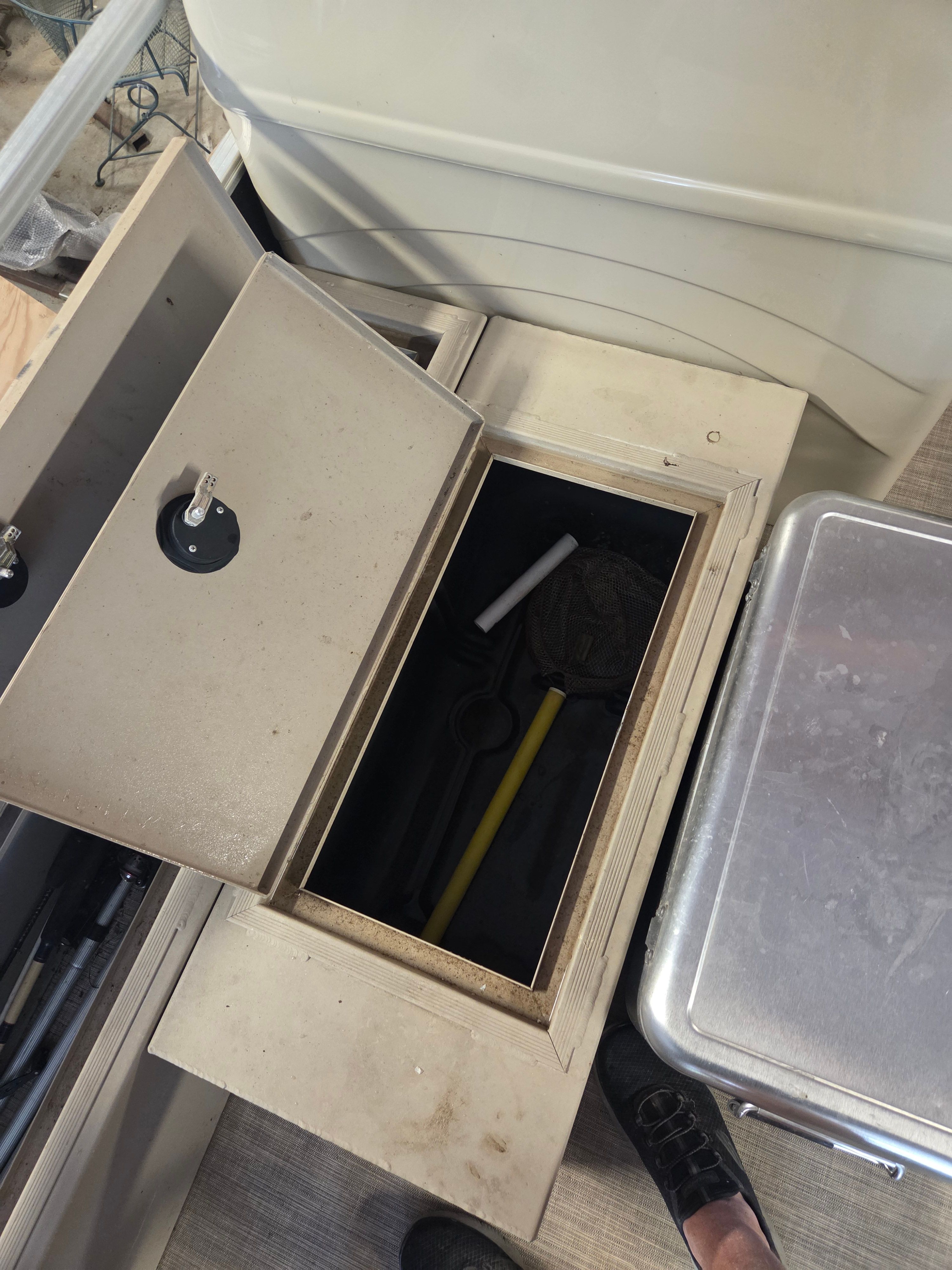 An open storage compartment on a boat with tools inside.