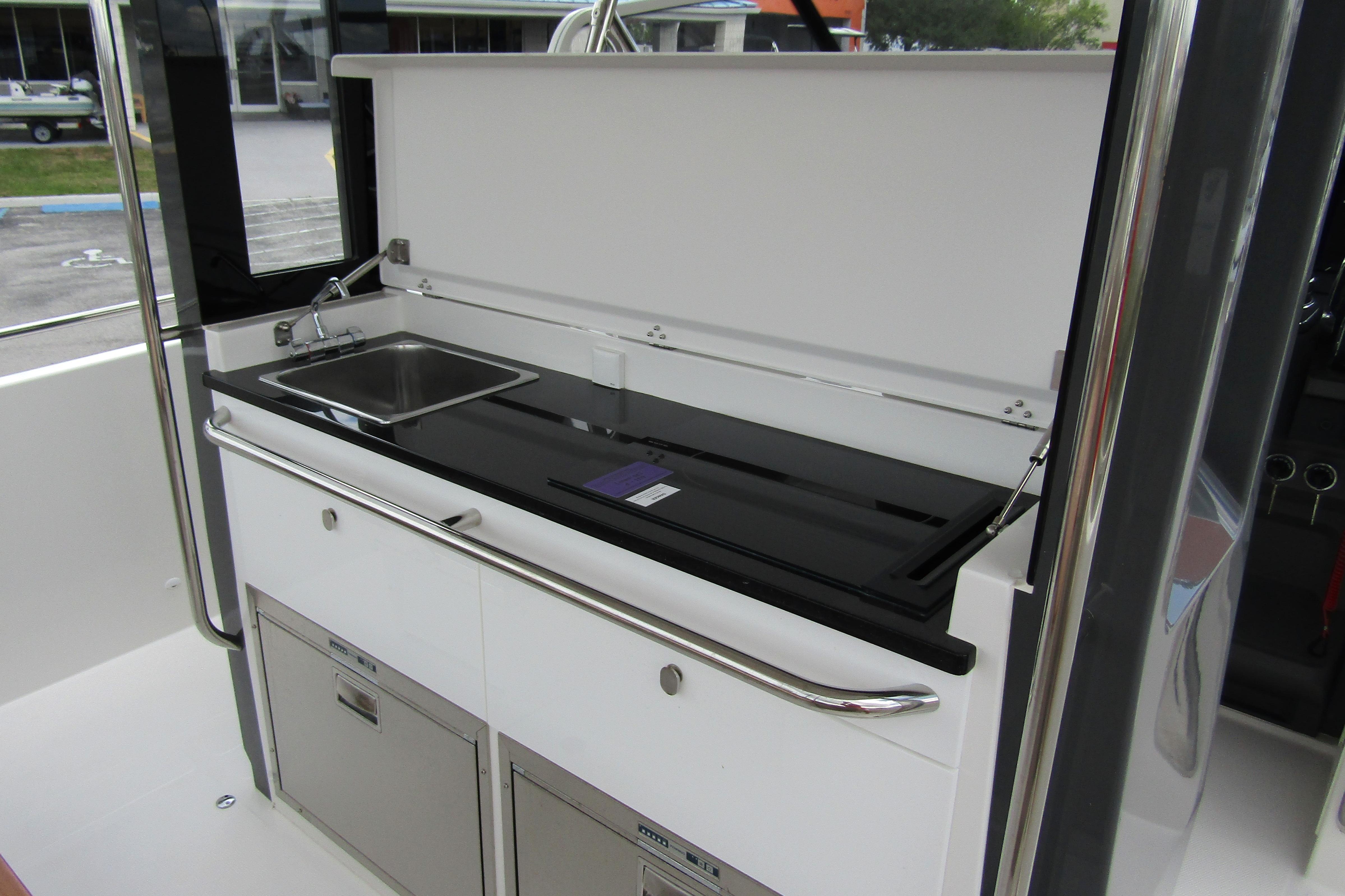 Modern kitchenette on 2025 Nimbus Tender 11 boat with sink and storage.