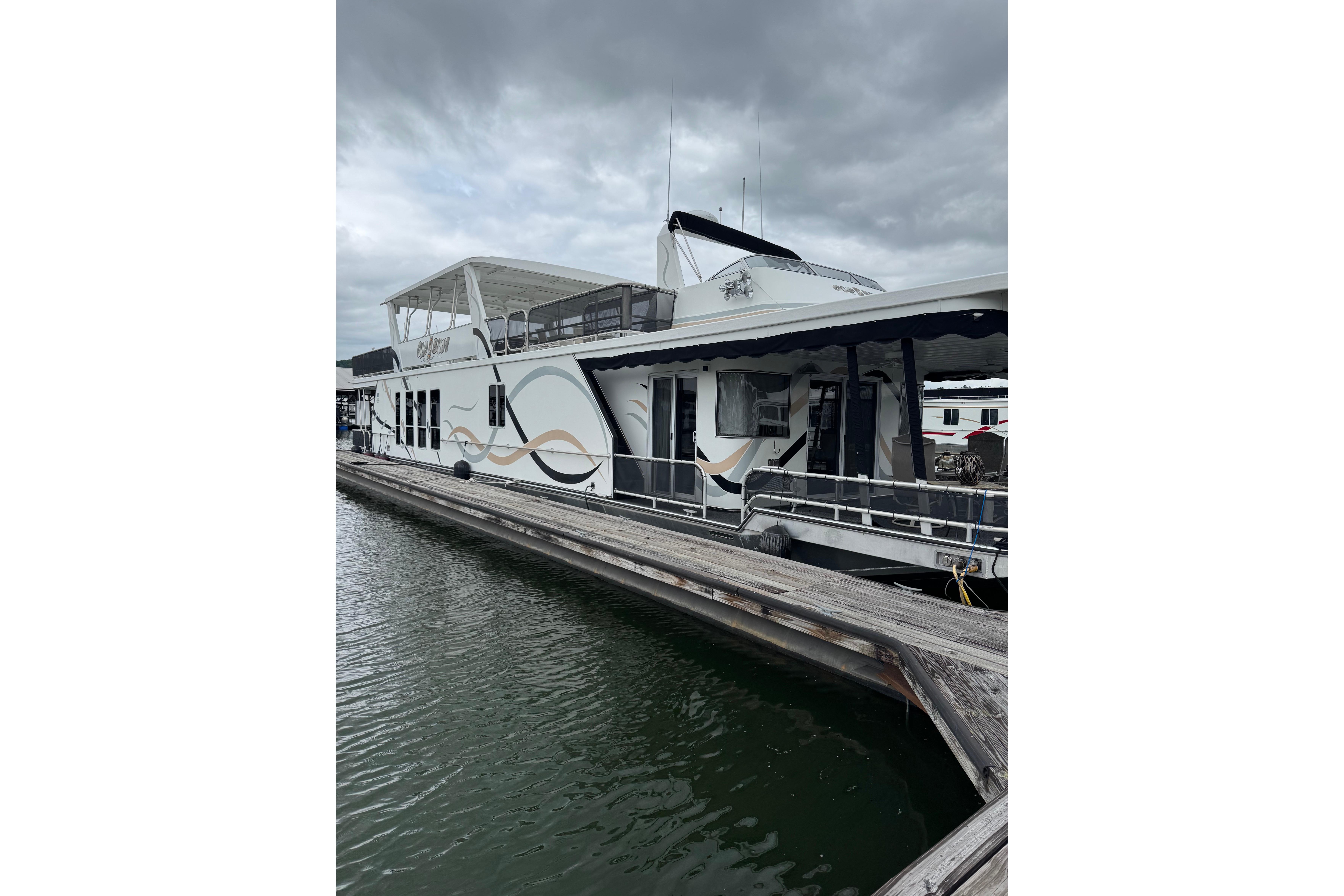 Houseboat docked at marina, Sharpe 80 X 18 model, 2001, under cloudy skies.