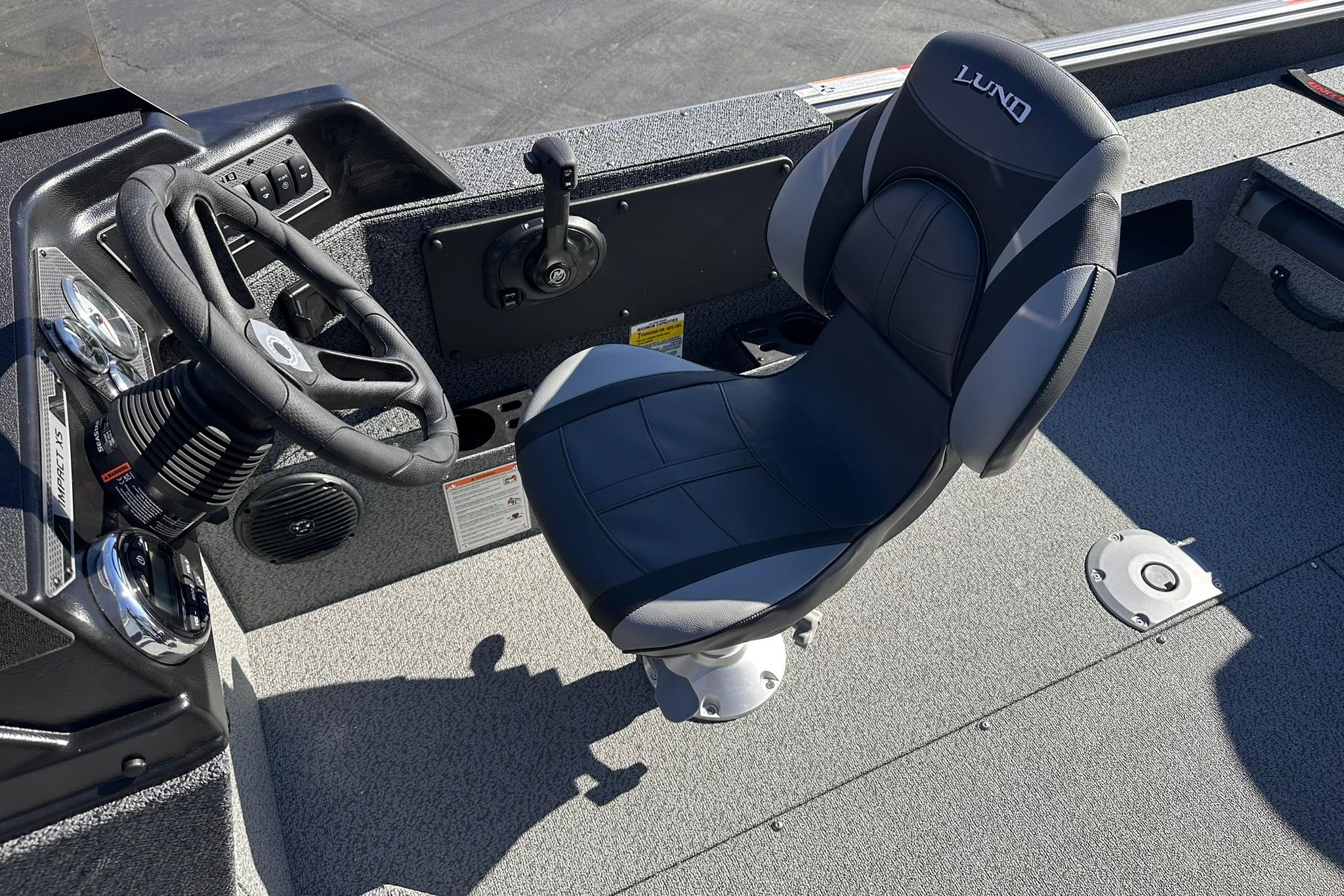 2026 Lund 1875 Impact XS SS boat interior with steering wheel and captain's chair.