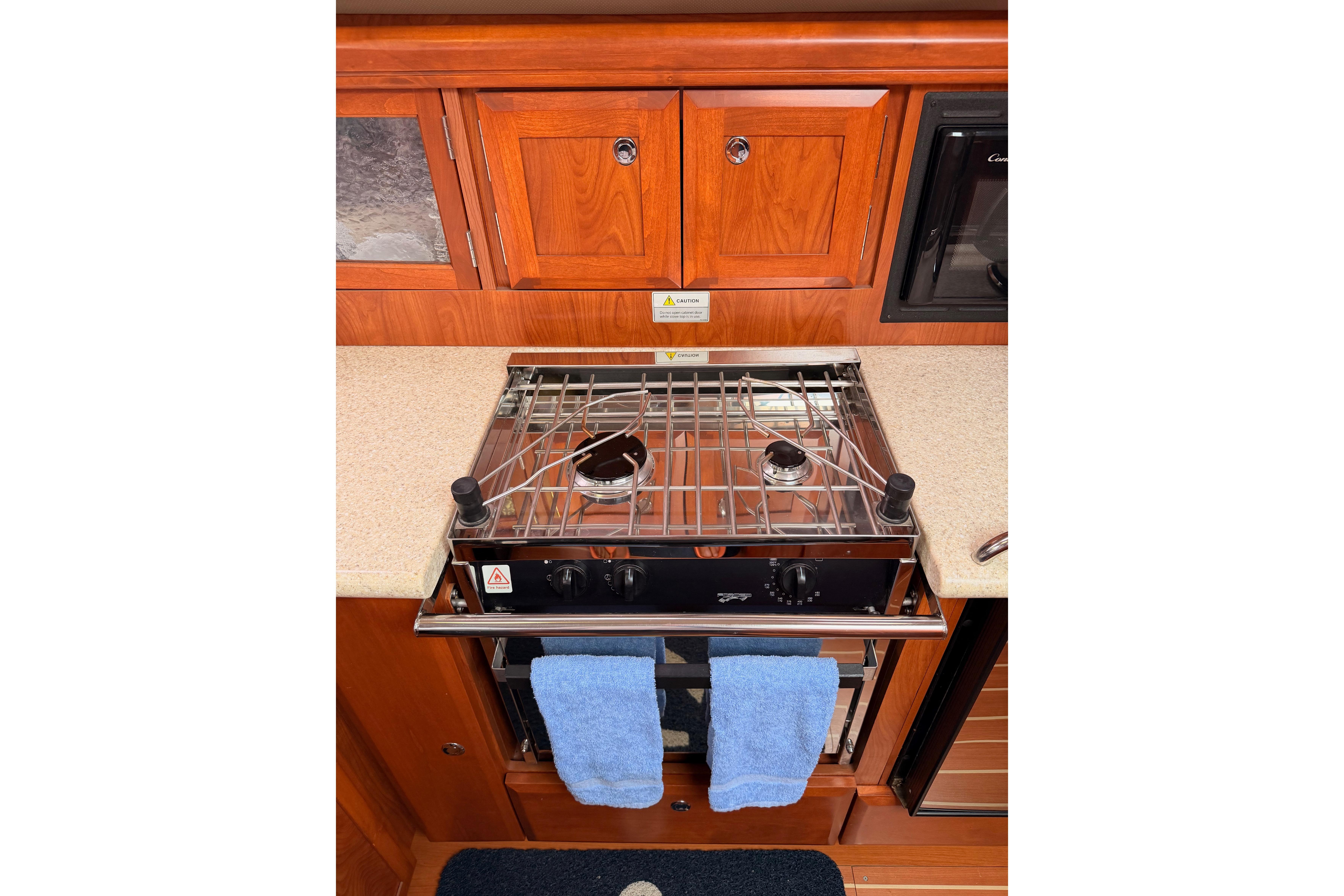Galley kitchen in 2009 Hunter 38 yacht with stove and wooden cabinetry.