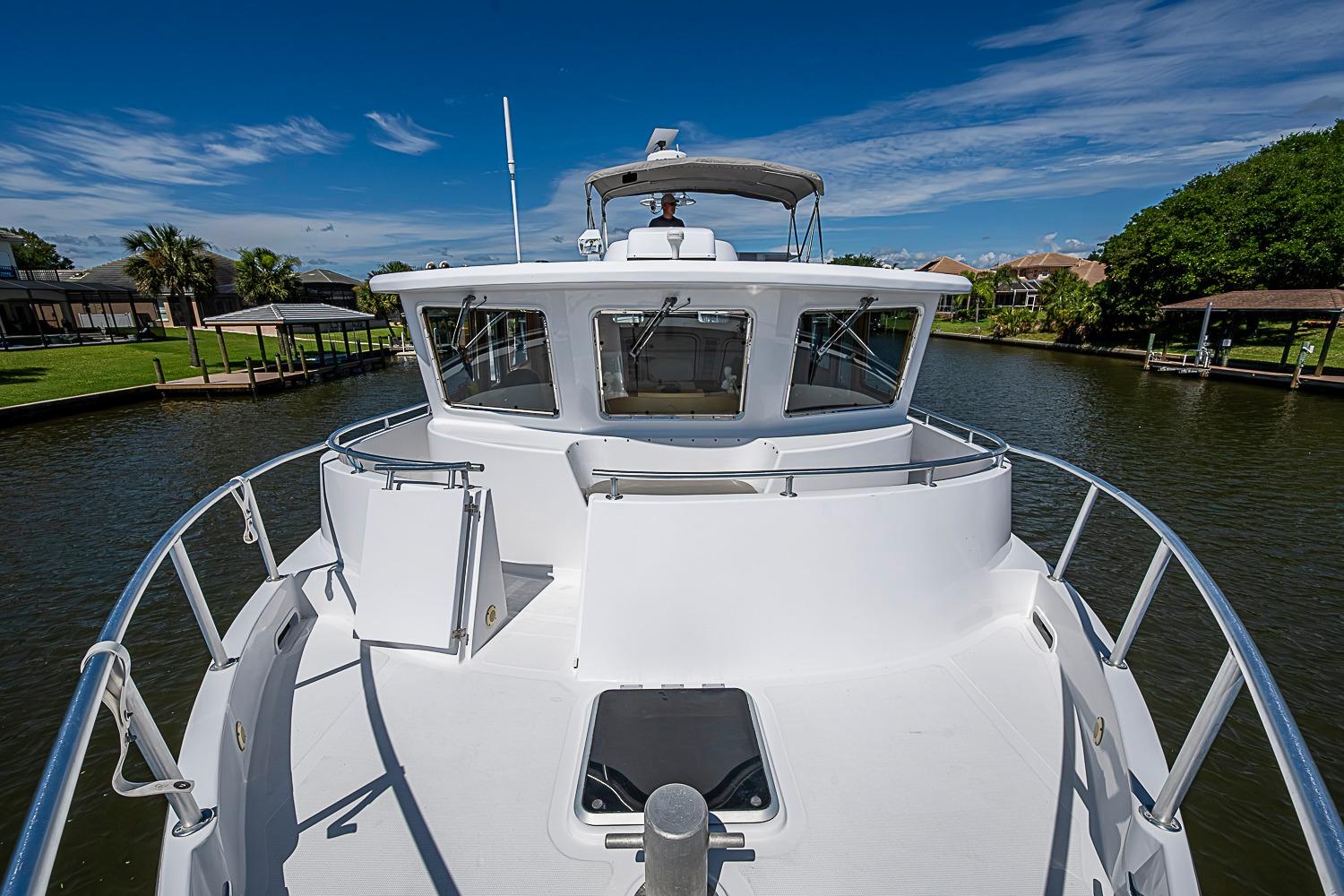 2003 Magna Marine Nova Scotia 47 yacht on a serene waterway under a clear blue sky.