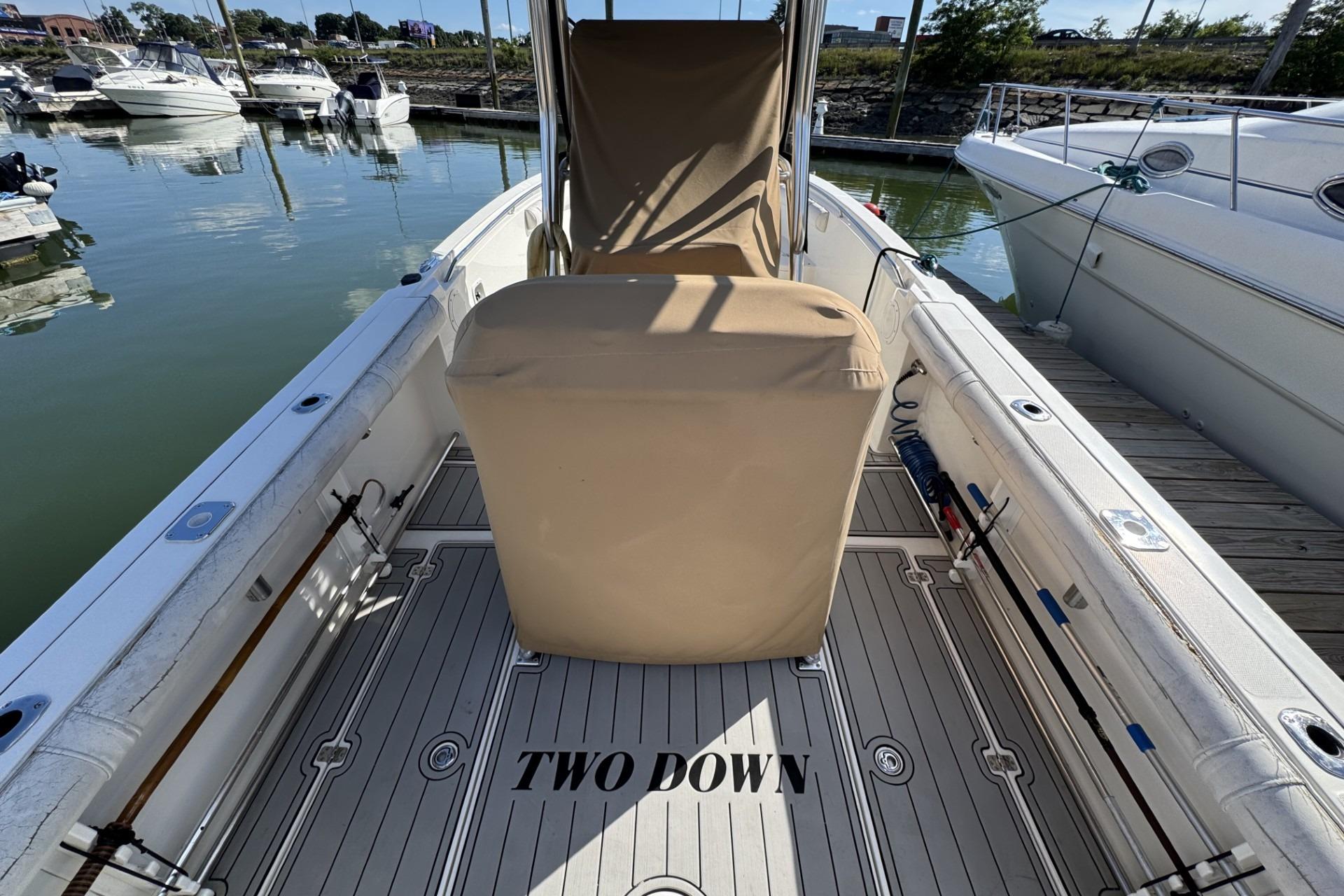 2007 Edgewater 245CC boat interior at marina, featuring covered seating and fishing rods.