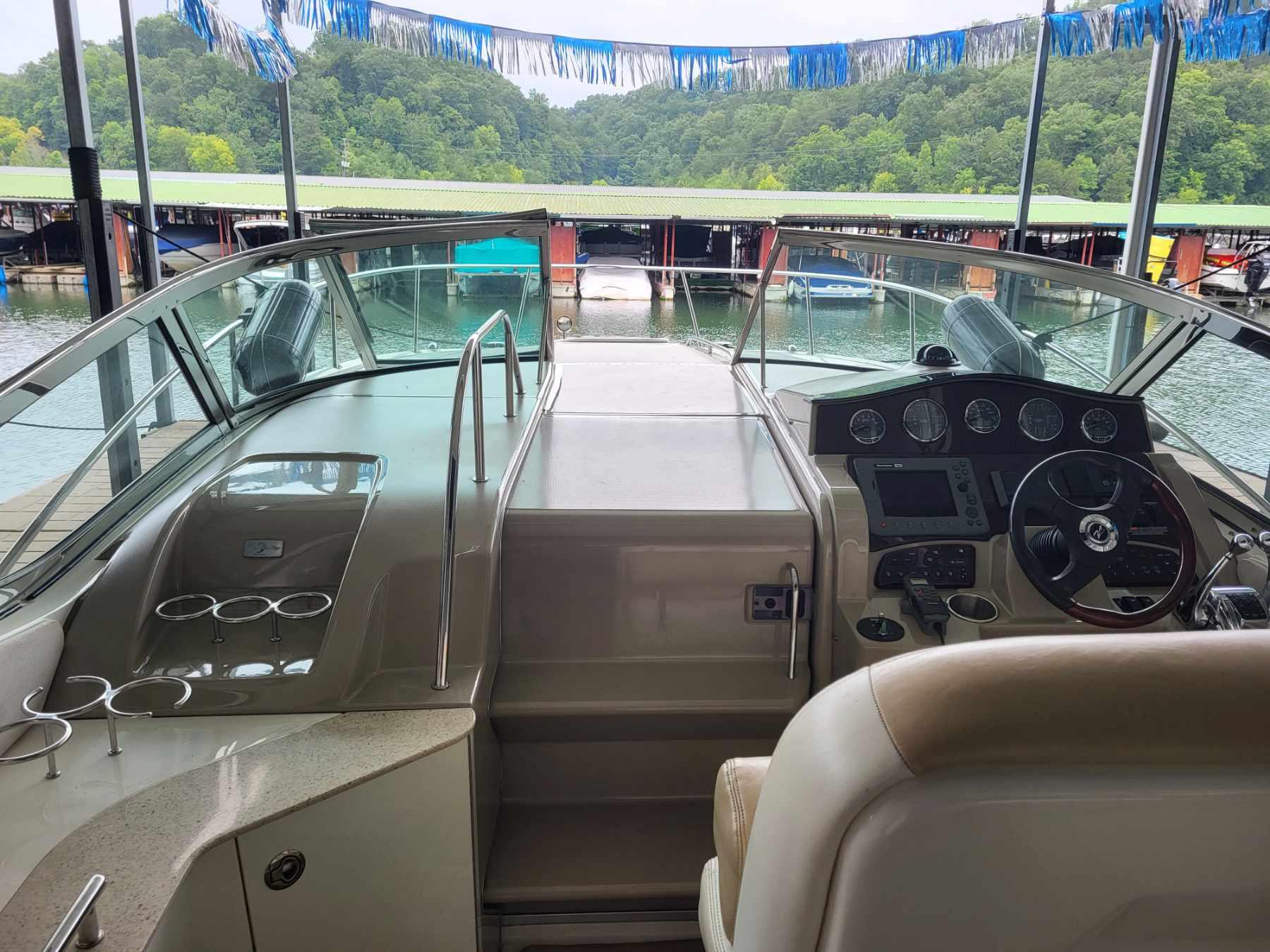 2009 Sea Ray 310 Sundancer cockpit with steering wheel, dashboard, and marina view.