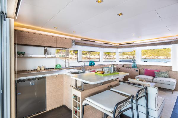 Luxurious interior of 2025 Lagoon 60 yacht with modern kitchen and seating area.
