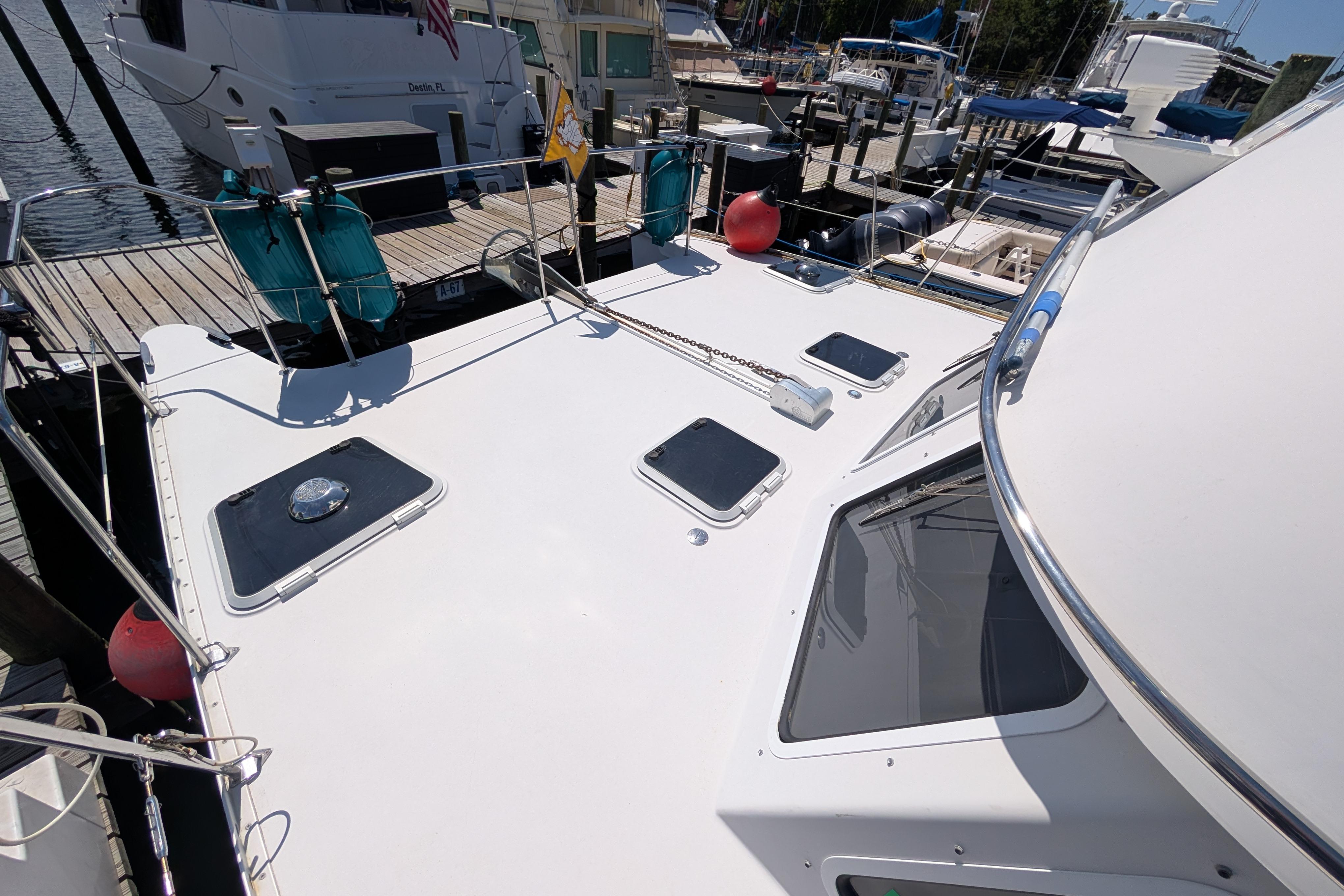2004 PDQ 34 Powercat docked, showcasing deck and hatches in a marina setting.