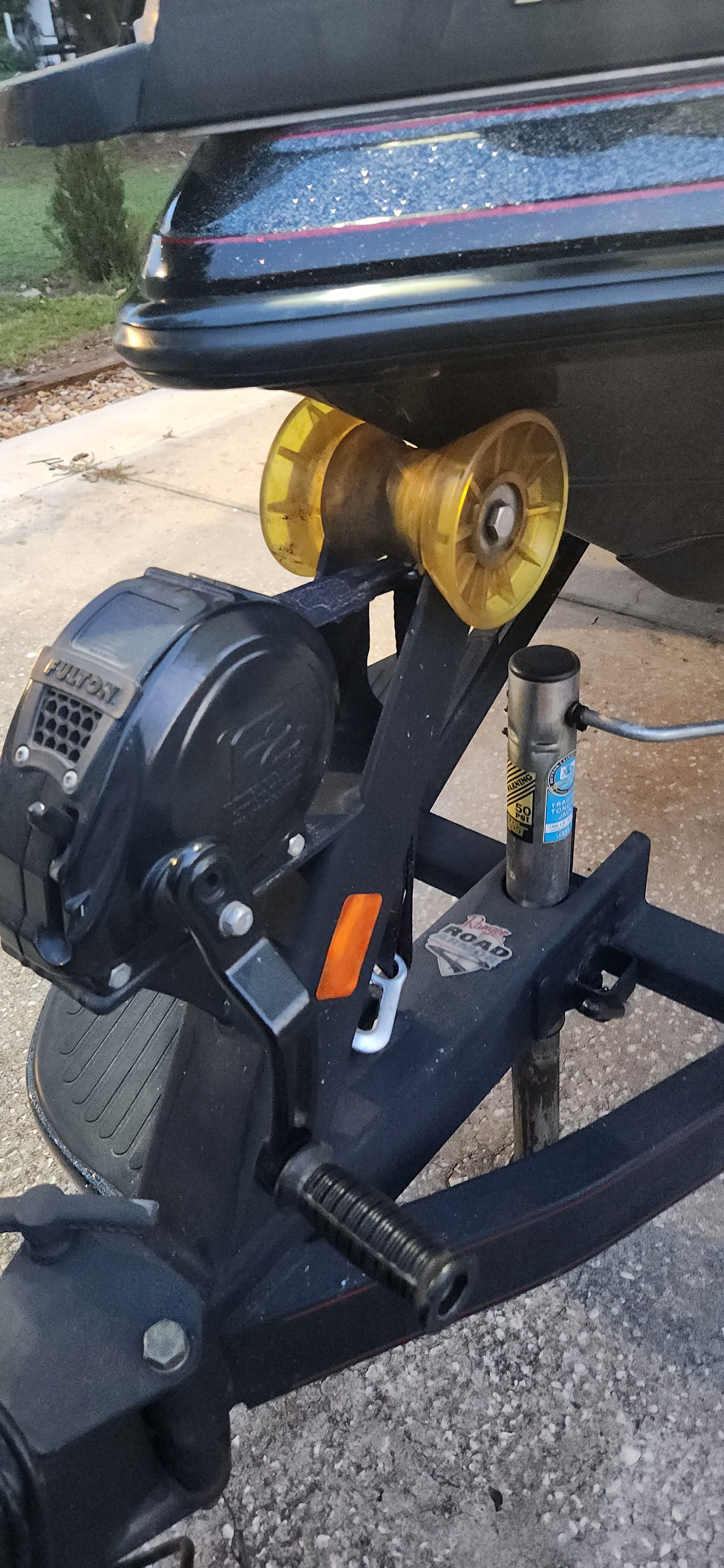 Close-up of a boat trailer with a yellow roller and a winch.