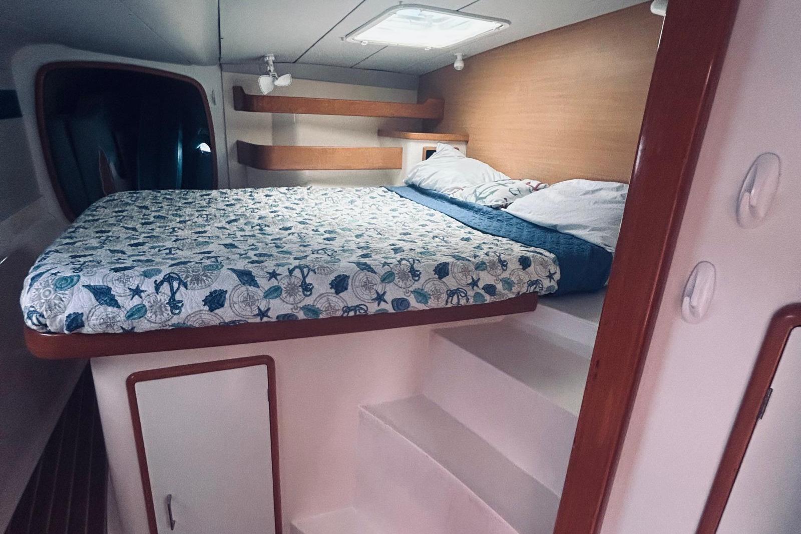Cozy cabin interior of a 2001 Robertson & Caine Leopard yacht with nautical-themed bedding.