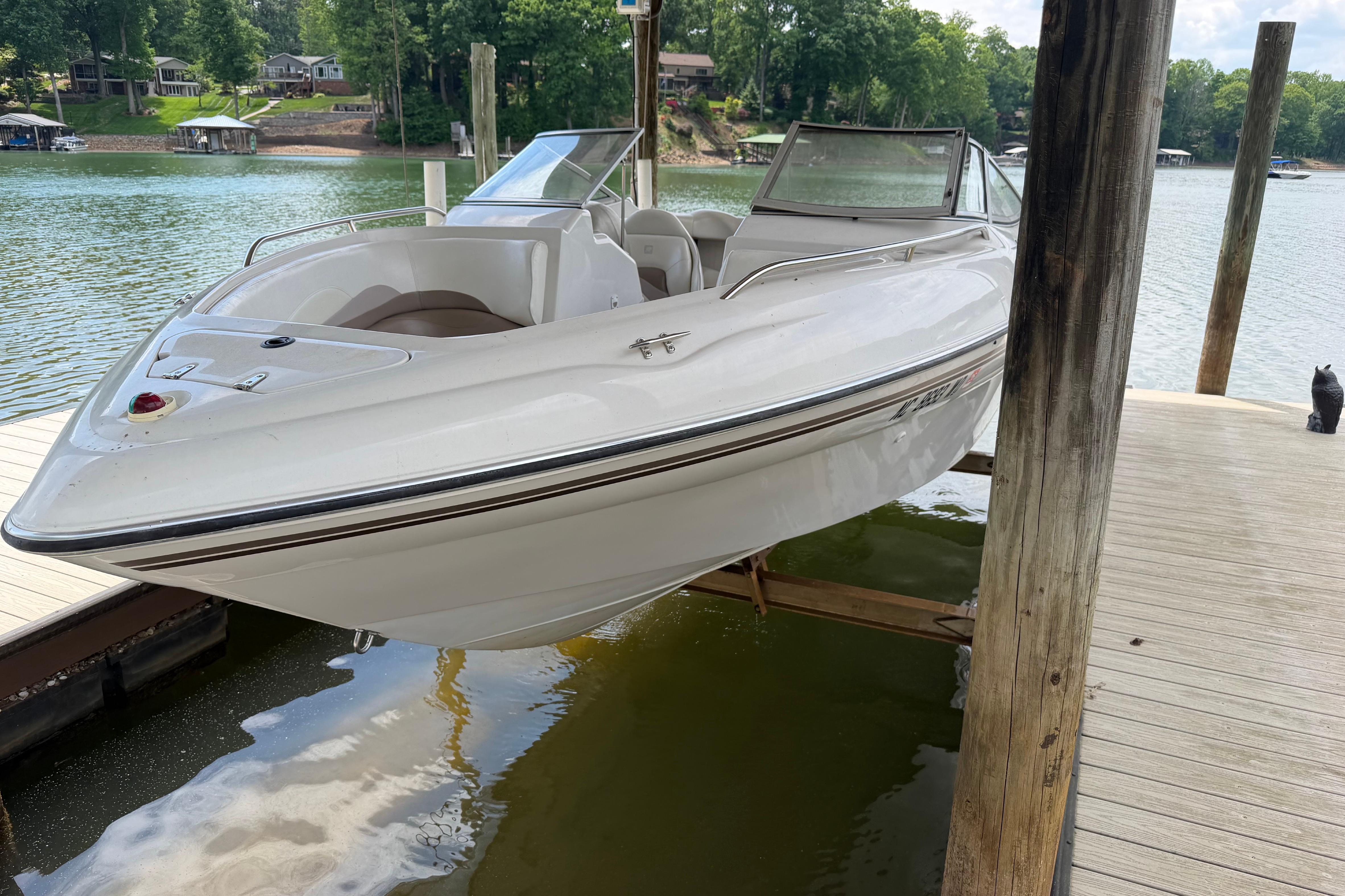1998 Four Winns 220 Horizon boat docked on a serene lake with lush greenery.