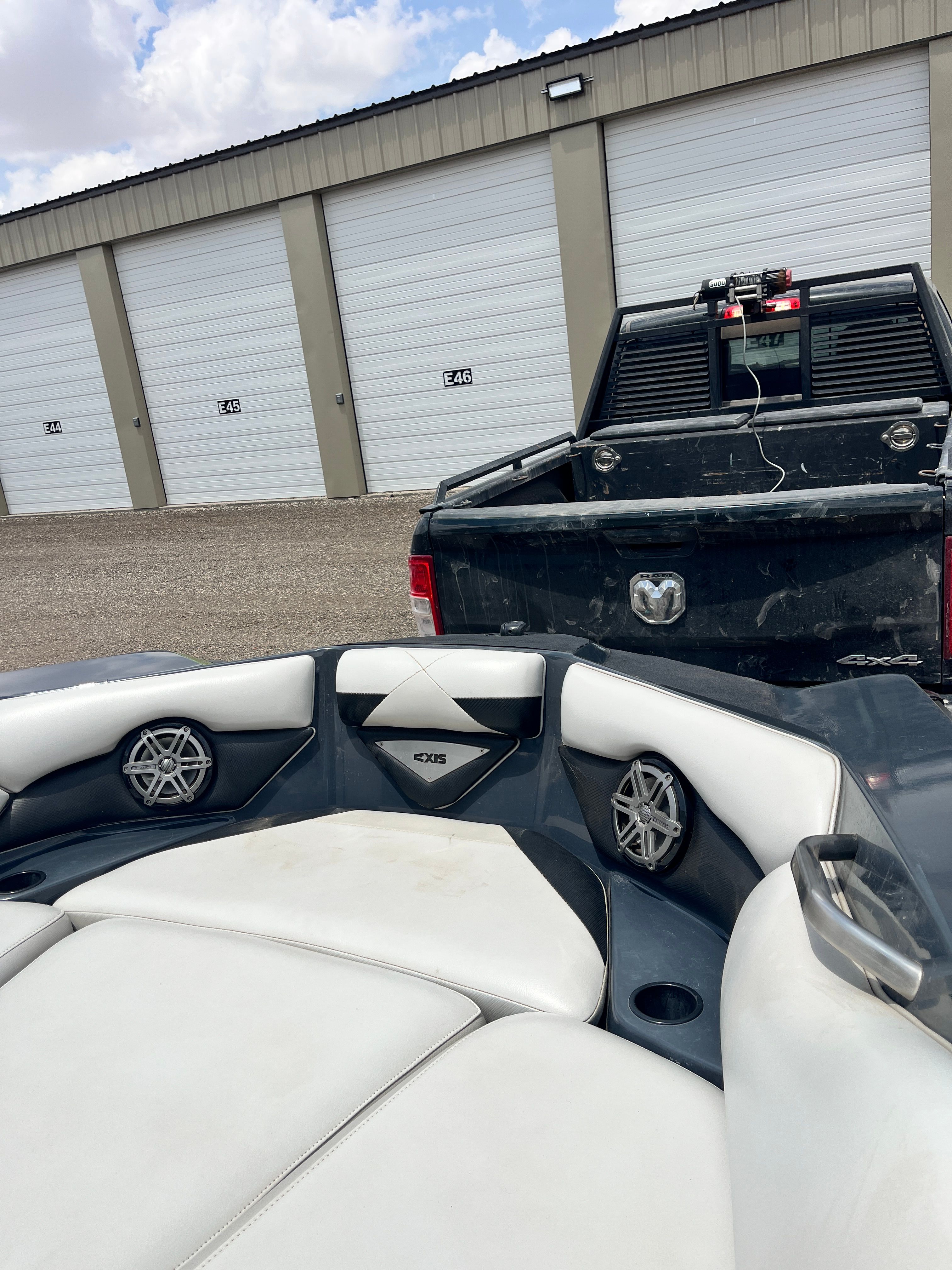 2013 Axis A22 boat near storage units and pickup truck.