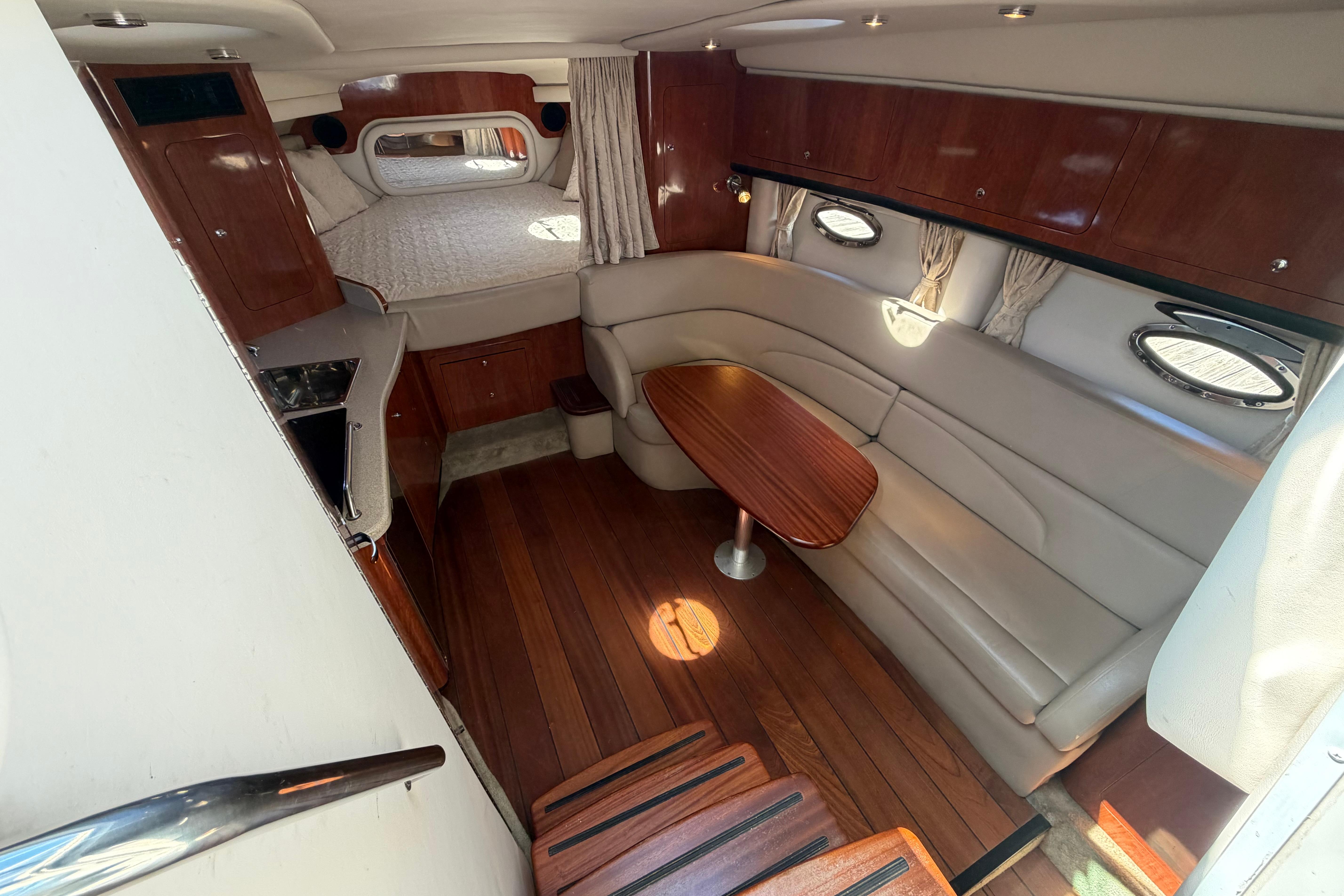 2008 Crownline 340 CR cabin interior with wood flooring, seating, and bed.